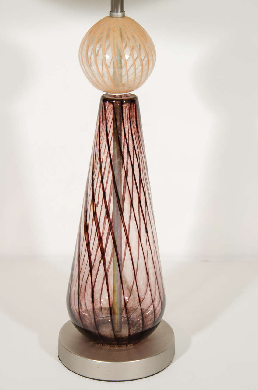 Elegant handblown Murano lamp with swirled glass design in hues of red wine or a dark purple. The lamp features a blown glass centre ball detail also with spiral designs hues of champagne or beige. The lamp has a silvered metal base with a satin