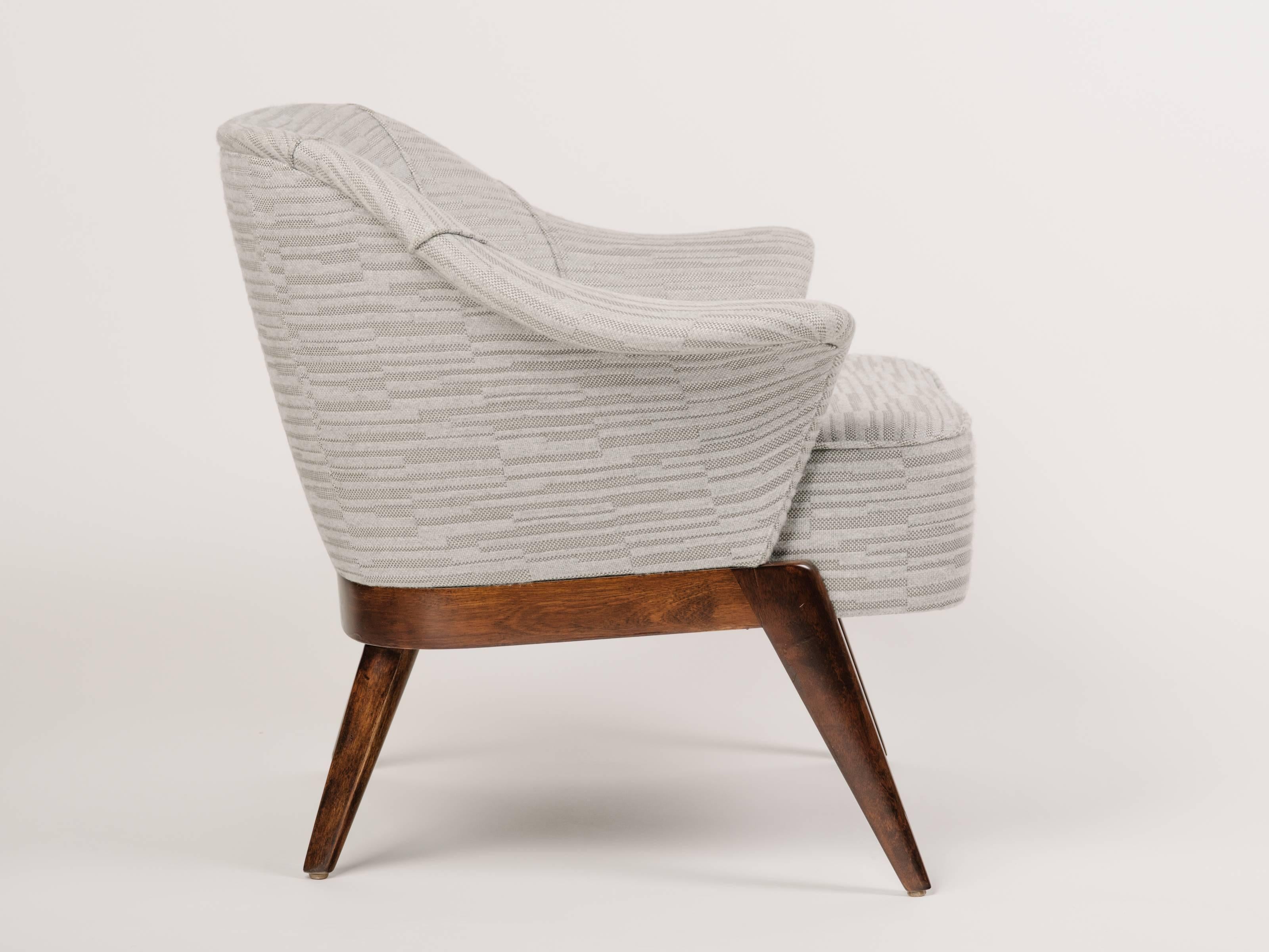 Outstanding Mid-Century Modern armchair with sculptural form. The chair has barrel form with winged swan sides and striking maple wood frame in walnut. Newly restored and upholstered in woven and embossed cotton-wool fabric with geometric pattern in