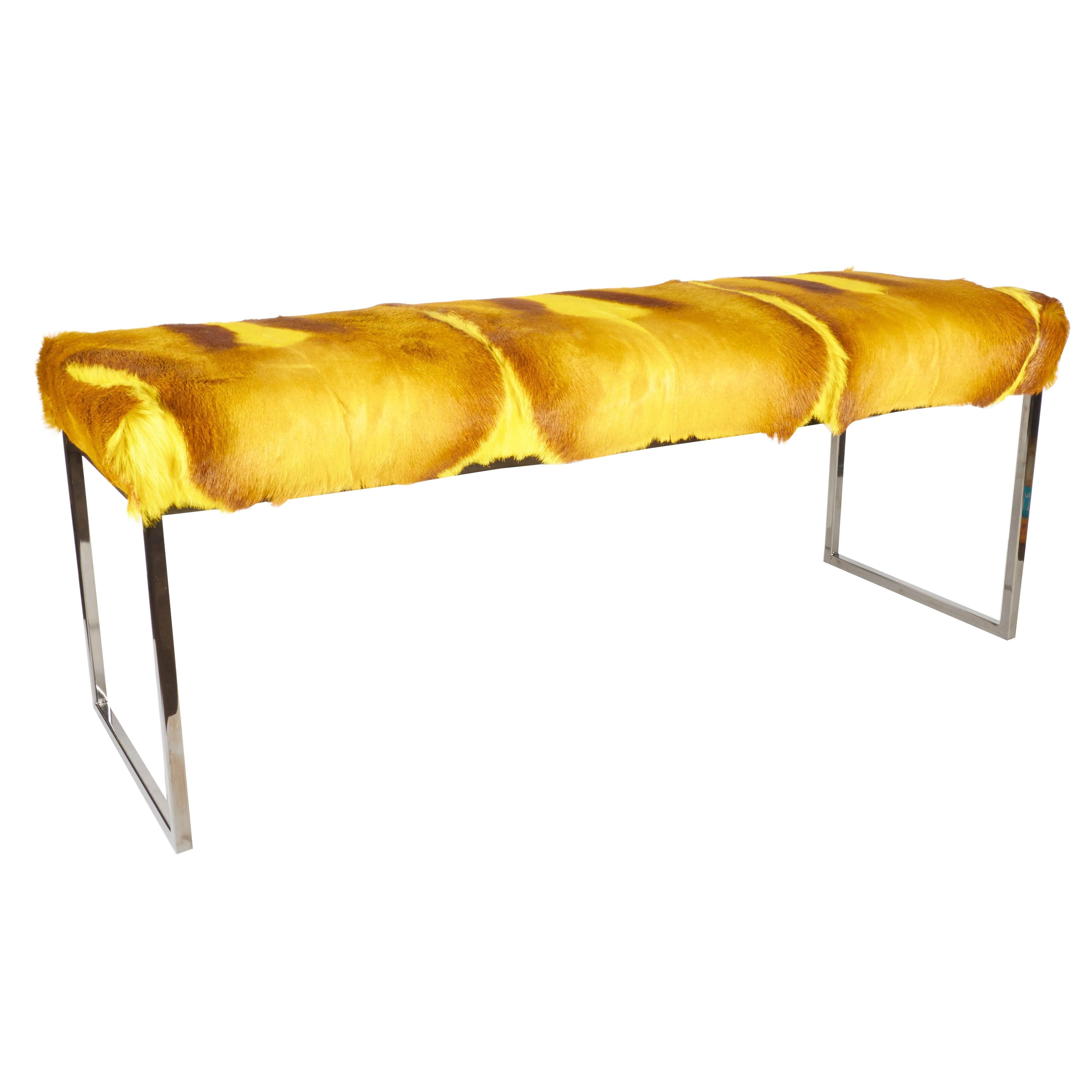 Mid-Century Modern style bench upholstered in stunning African springbok hide. Comprised of several hides featuring four spine details. Hand-dyed in vibrant yellow with varying hues of gold and deep brown. Streamline base in a black nickel finish.