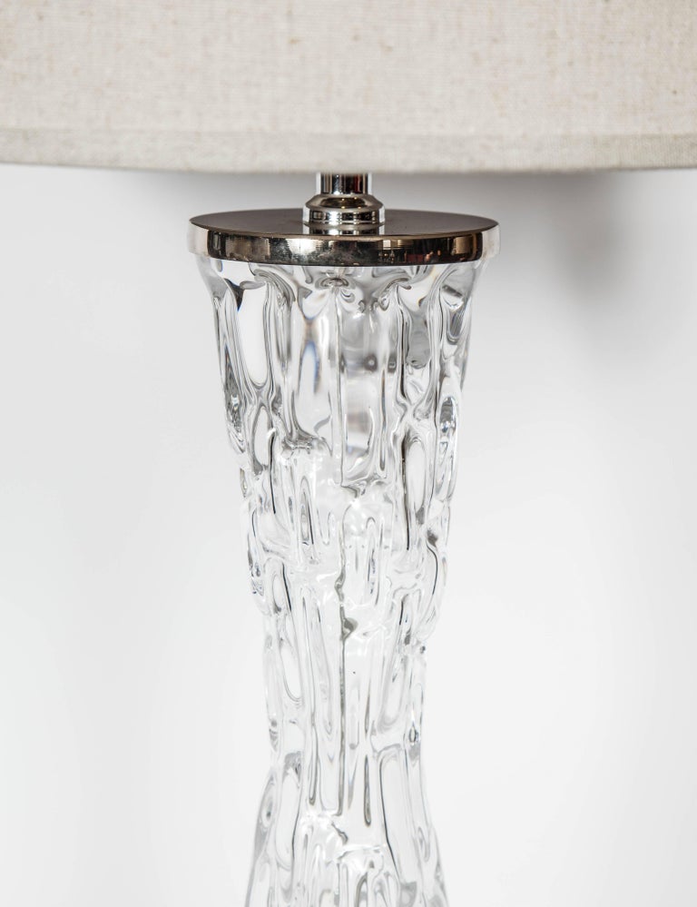 Gorgeous hand blown crystal glass lamp with highly stylized hourglass form. The lamp features faceted ice glass design and has polished nickel hardware and fittings. Newly rewired and shown with elegant linen drum shade in grey sand. Signed Orrefors.