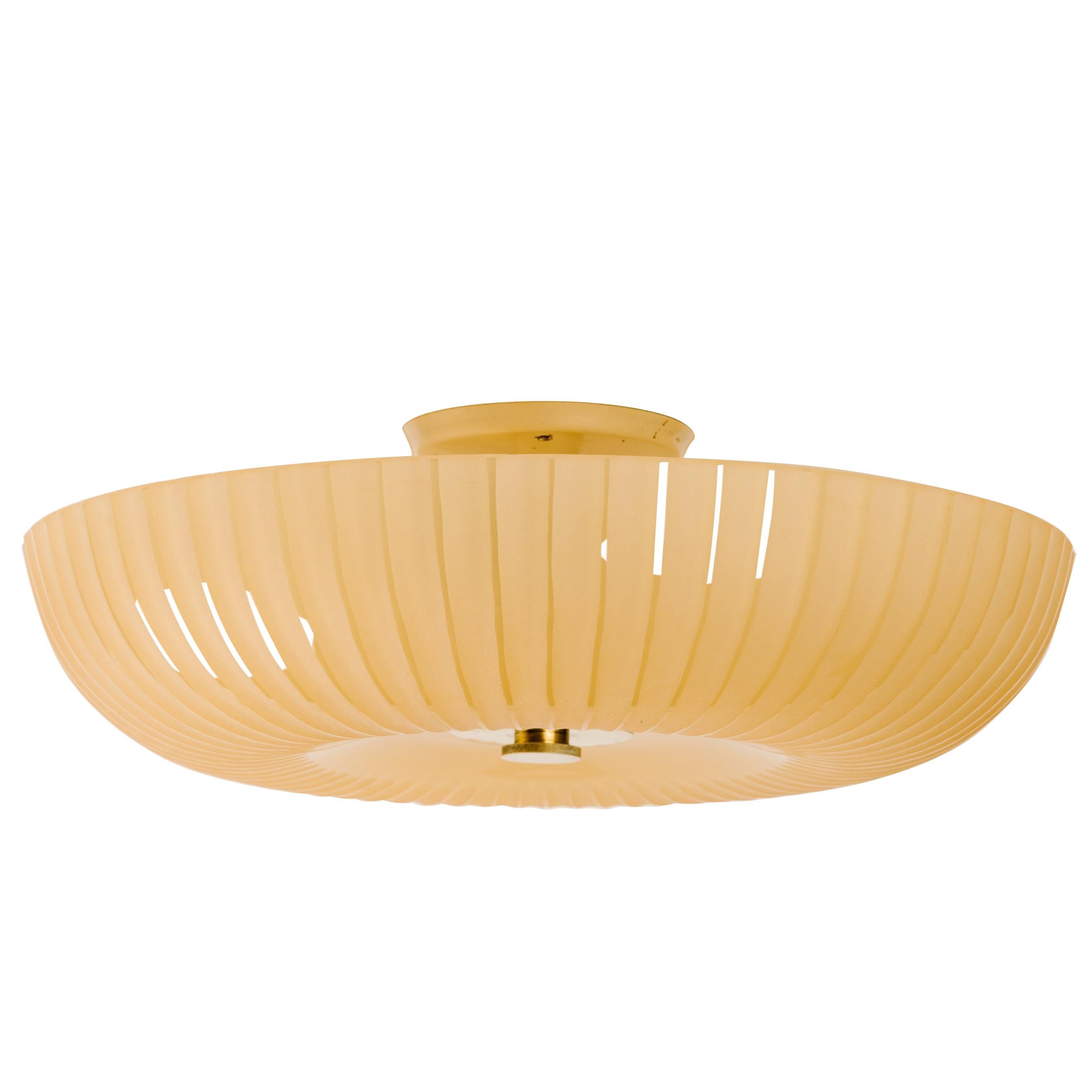 Rare Mid-Century Modern amber glass flush mount. Large sand blasted frosted glass dome with fluted details. The chandelier has patinated brass fittings and enameled metal light sockets. Fitted with three lights. Large circular ceiling plate in ivory
