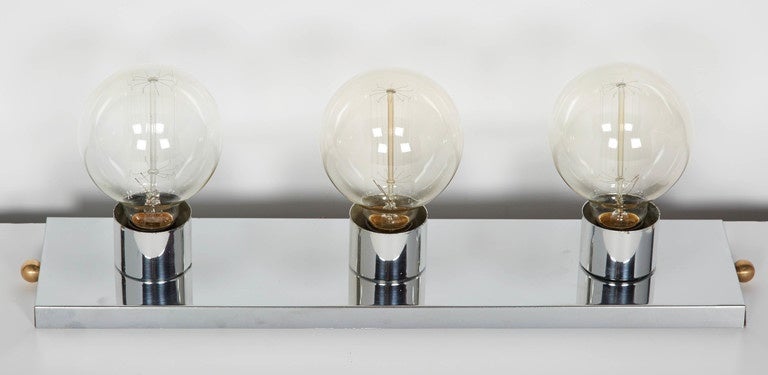 Vintage modern wall light featuring a polished chrome frame with brass ball finials. Fitted with three large thread filament globe light bulbs, which creates an atomic inspired design. The chrome has a magnificent mirrored effect - perfect for a