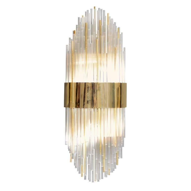 Outstanding modernist sconce comprised of glass and gold-plated rods in alternating heights, creating multiple tiers. Has a sculptural design with Art Deco skyscraper elements. Features a large brass center banded detail as well as a brass frame and