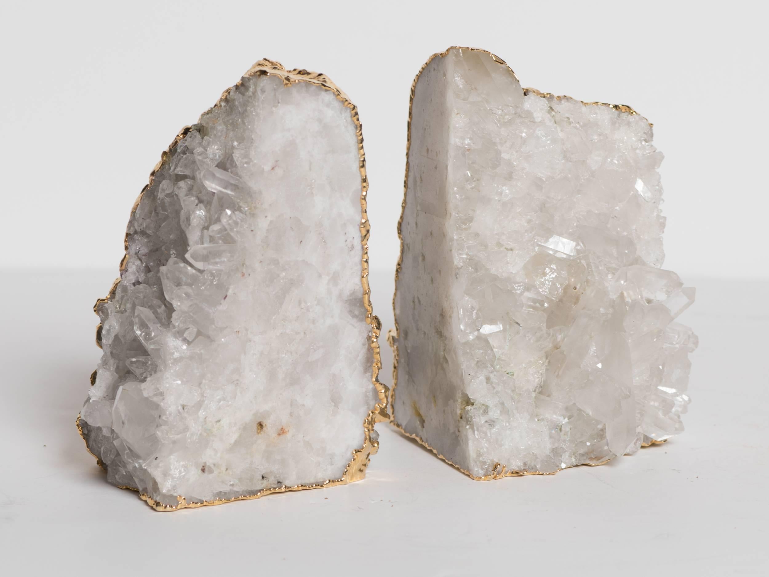 Outstanding pair of rock crystal quartz specimens with rough edges wrapped in 24-karat gold plating. Can be used as bookends or as decorative objects. Exquisite natural forms with protruding wedges of quartz throughout. Stunning from all angles and