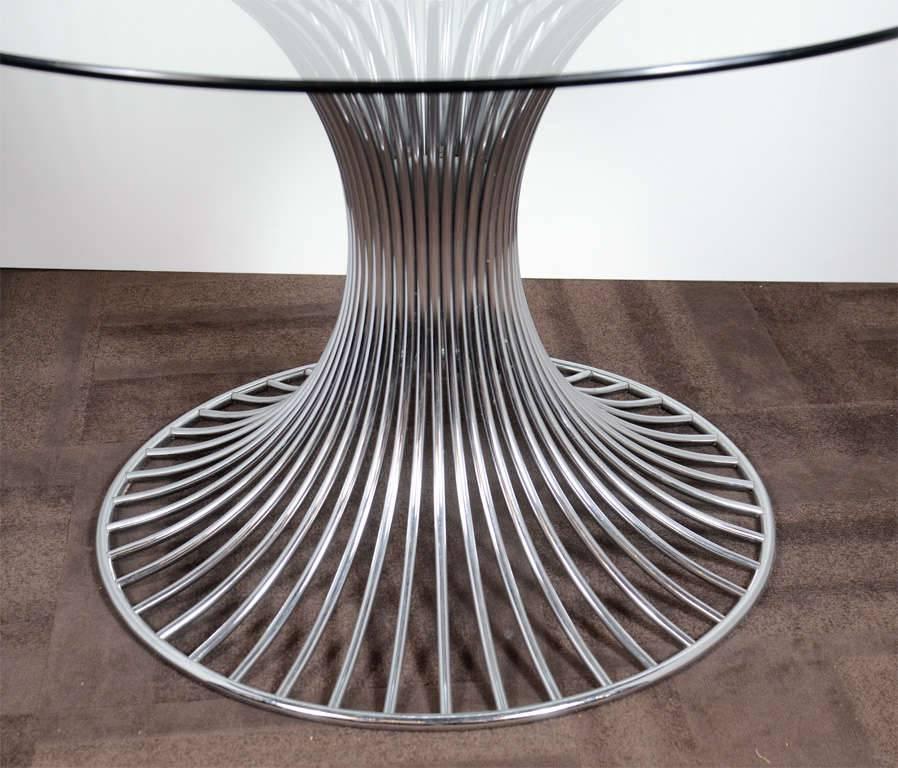 Outstanding Mid-Century dining table has a sculpted tubular chrome base and features a round glass top. Distinguished tulip table design, exemplary of architectural designs of the 1960s and in the style of Warren Platner.