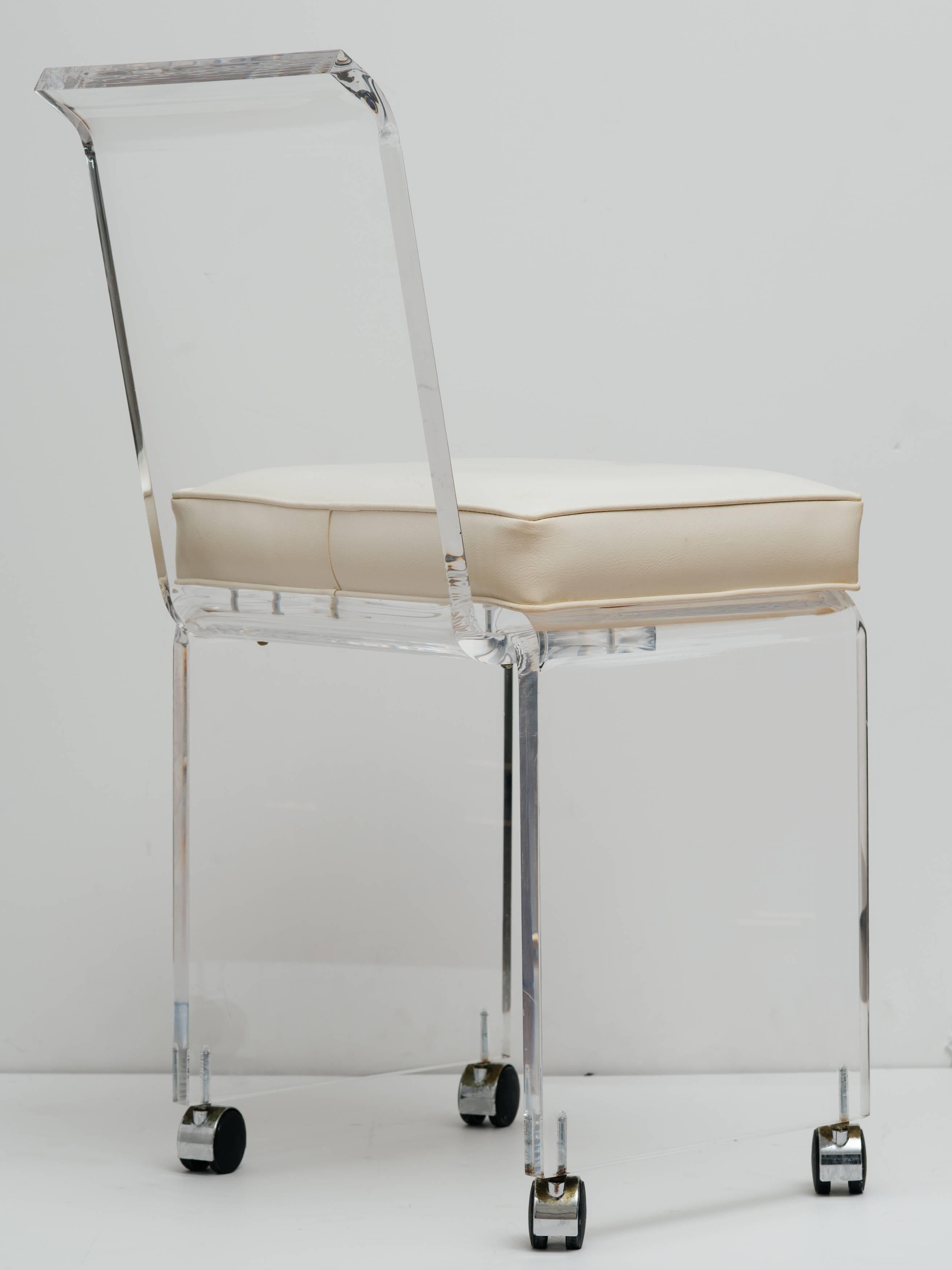 Mid century modern lucite vanity chair with full back design. The vanity stool has a sleek streamline design with polished beveled edges. Features swivel casters for effortless movement. Shown with original white naugahyde seat. Price includes