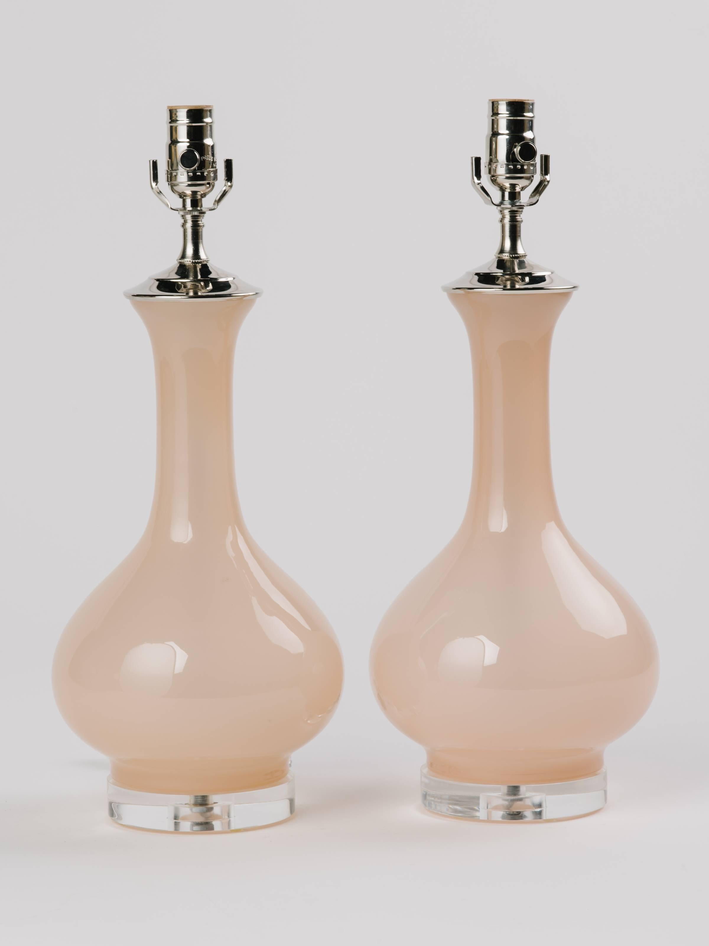 Pair of pale pink opaline glass lamps. Lamps have elegant baluster vase forms. Fitted with circular Lucite bases and polished nicked fittings. Shown with custom linen drum shades in off-white. Newly rewired.