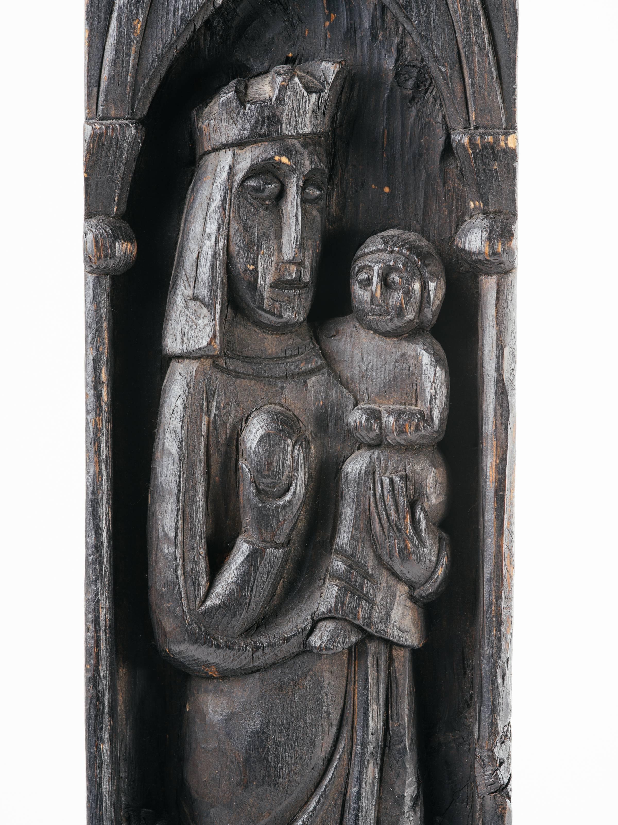 Victorian monolith wood plaque with hand-carved relief design depicting the Virgin Mary and baby Jesus.  The carving features Gothic arches and columns with floral shields along the bottom. Has ebony finish and fitted with small hook for wall