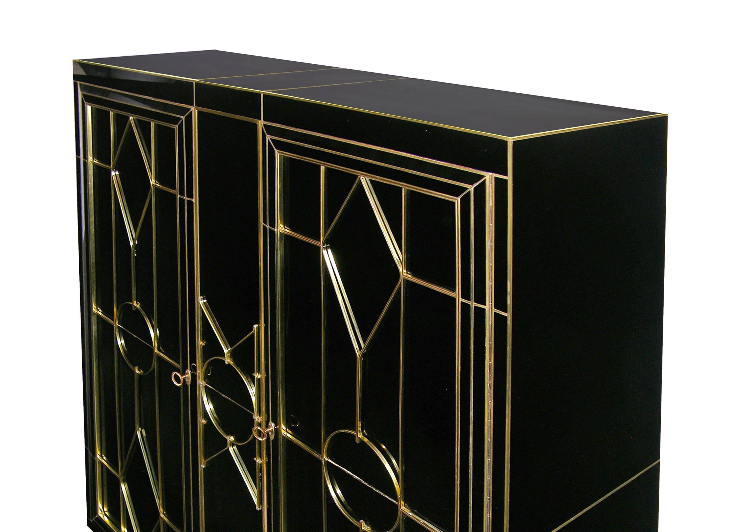 This late 1970s one-of-a kind Italian cabinet, from the North of Italy, entirely handmade, is covered in black glass highlighted with brass inlays. It is skillfully hand decorated with a bronze raised pattern on the front. The two doors are enclosed