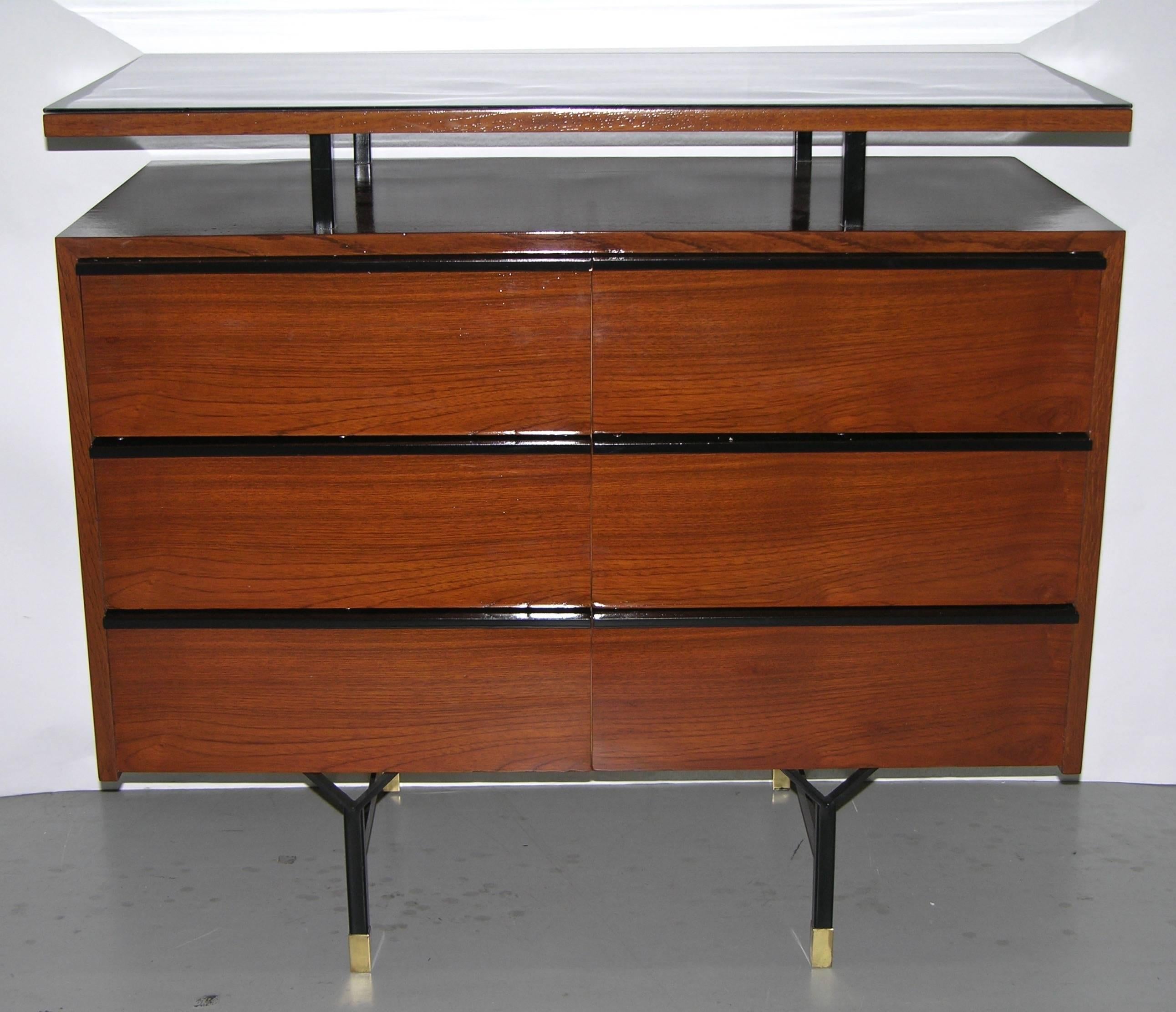 Sleek modern functional design for this six-drawer dresser finished in high-quality teak wood veneer on sling shaped black lacquered metal legs with a brass foot. The black metal lines on the front cleverly perform as geometric outlines and as