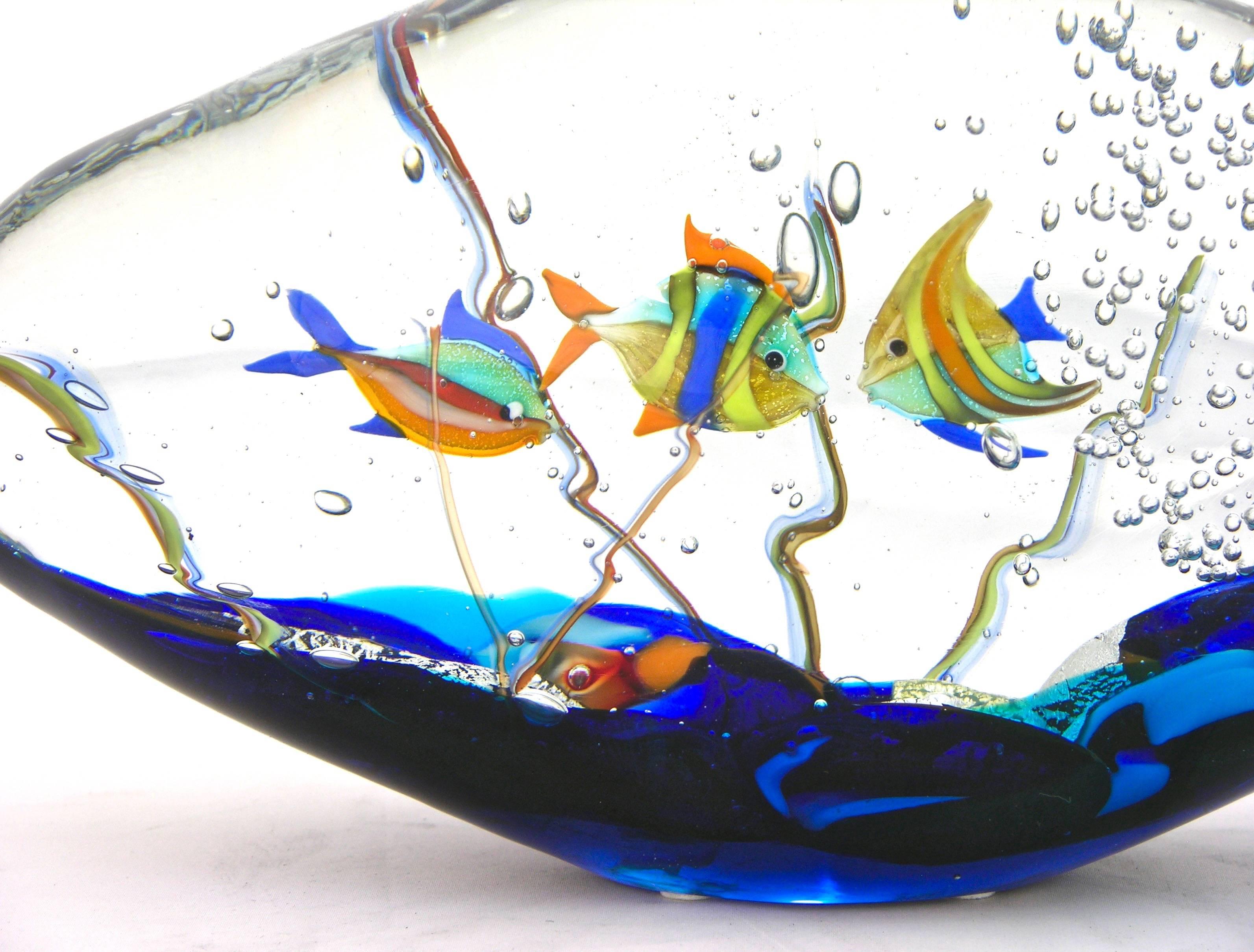 This aquarium sculpture in blown Murano glass is signed by Alberto Dona', decorated with three tridimensional colorful fishes amongst bubbles rising from a blue sea bed highlighted with pure silver leaf. High quality of details and attractive oblong