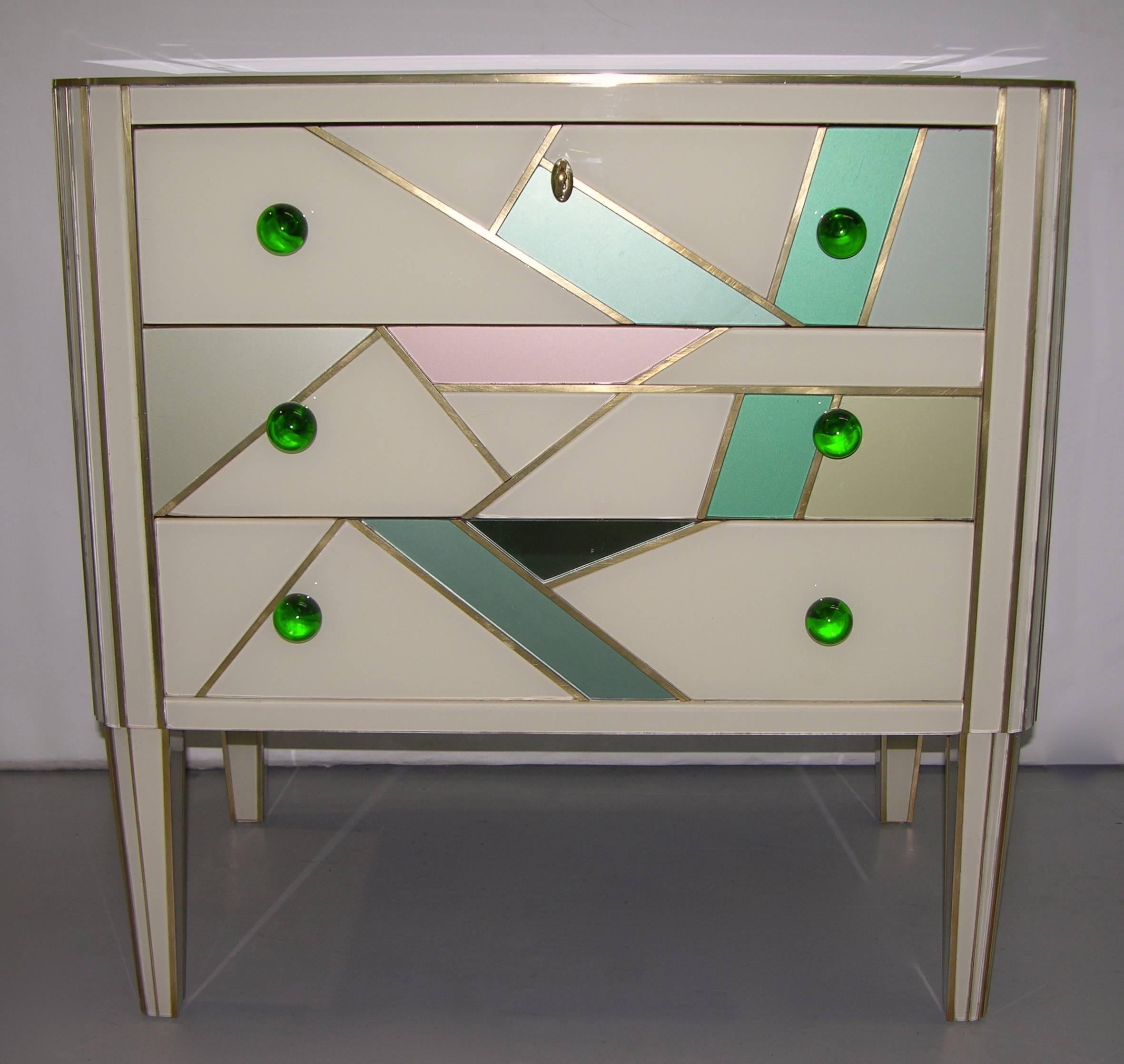 1980 very interesting and refined Italian pair of three-drawer side tables or nightstands, entirely handmade, the whole surround in ivory glass, decorated with a unique and reverse abstract design of mirrored and colored glass geometrical shapes,
