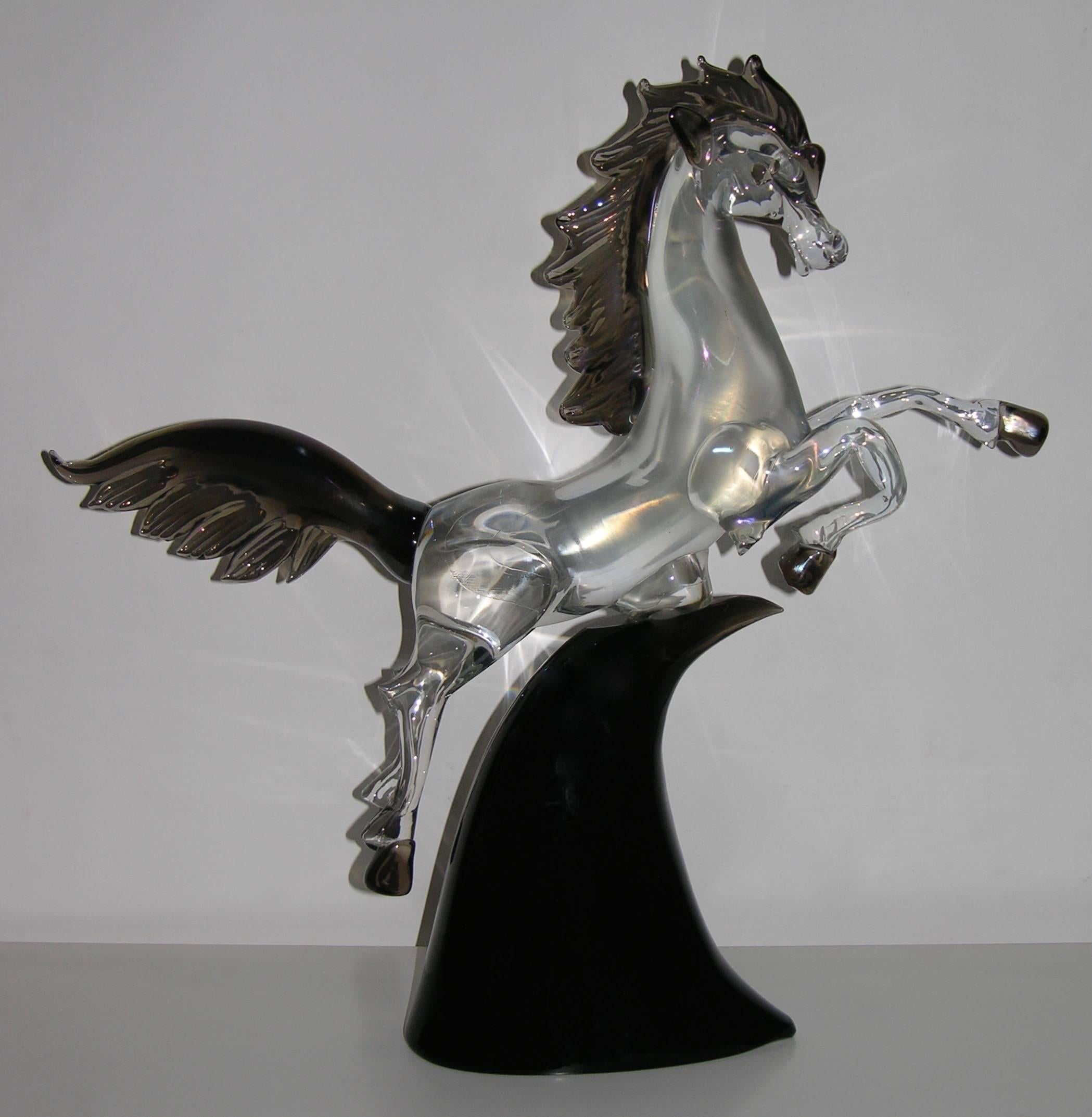 A work of art signed by Licio Zanetti, a jumping horse in clear Murano glass worked with iridescence, with smoked mane, tail and hoofs. The iridescence creates changing shades of tones that give life and movement to the animal, raised on an