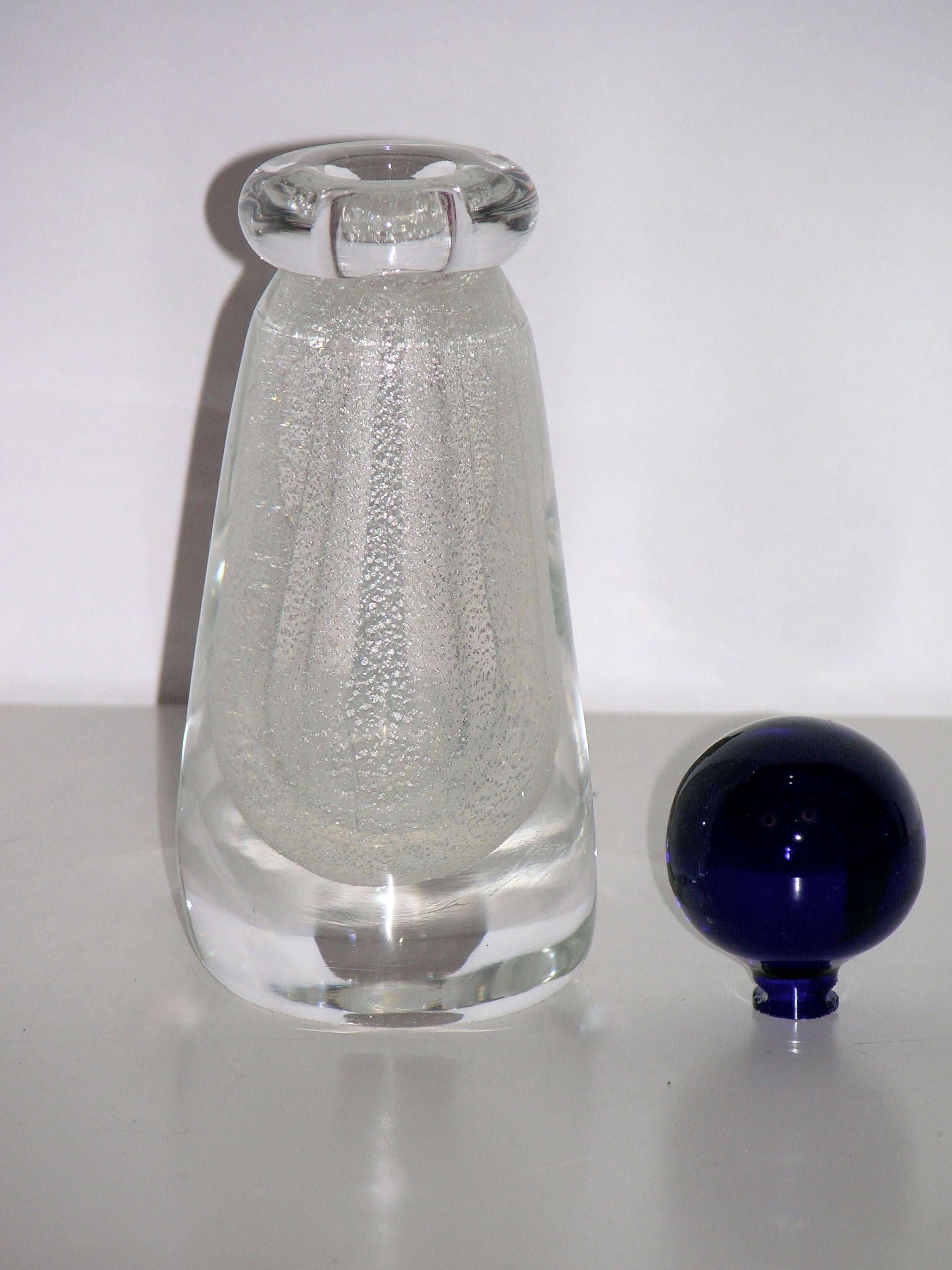 1980 Murano glass bottle by Formia, signed. The clear body is worked with pure silver speckles in the overlaid glass, cleverly accented by a lipped neck in clear glass accompanied by its original stopper in a night blue color.