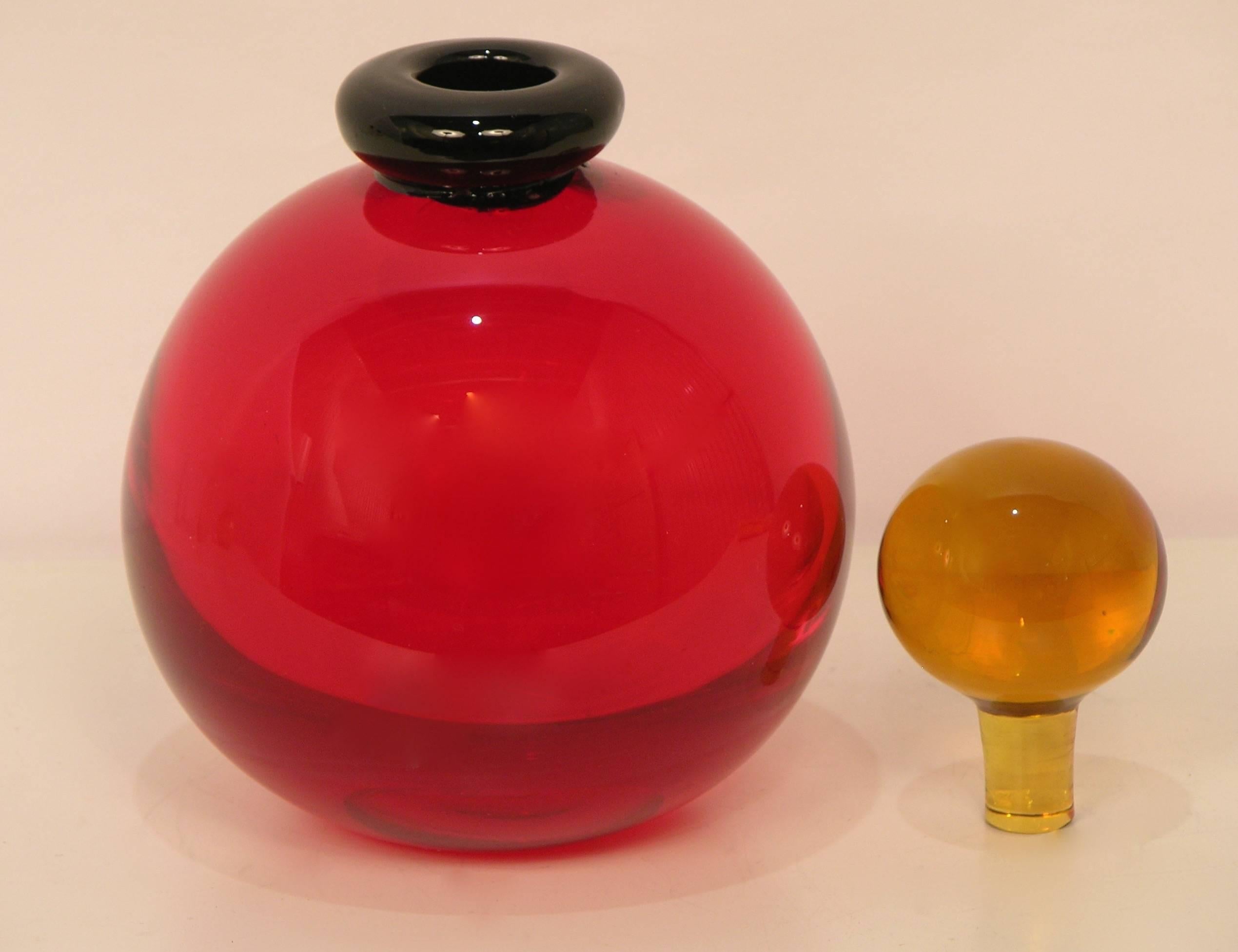 1970s Murano glass bottle by Archimede Seguso, signed. The blown red body is perfectly round, cleverly accented by a lipped neck in black glass accompanied by its original stopper in deep good glass.