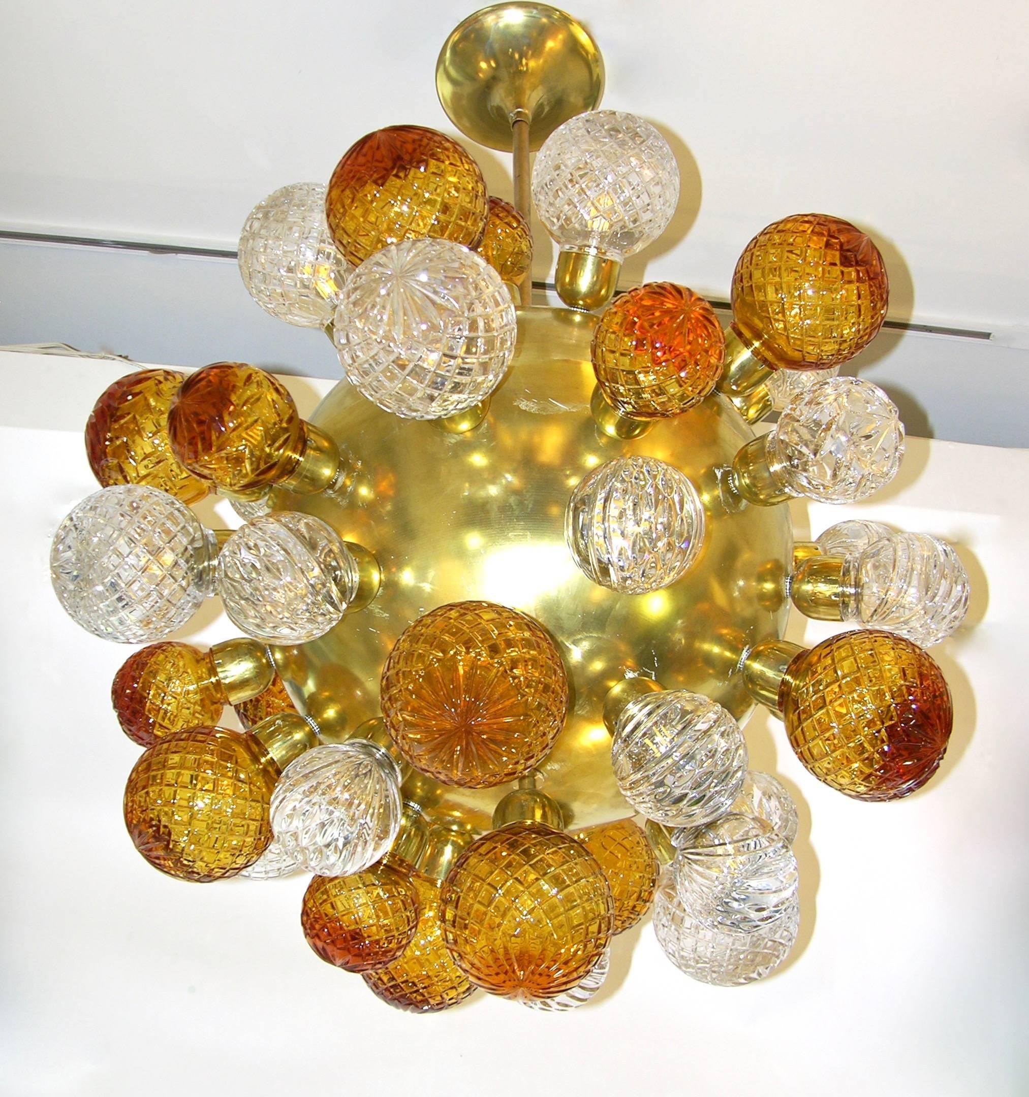 A whimsical one of a kind chandelier of unique design, entirely handmade in Italy, circa 1980, the central round bronze core is decorated with protruding Swarovski clear and amber gold cut crystal balls. The exceptional quality of the crystal and