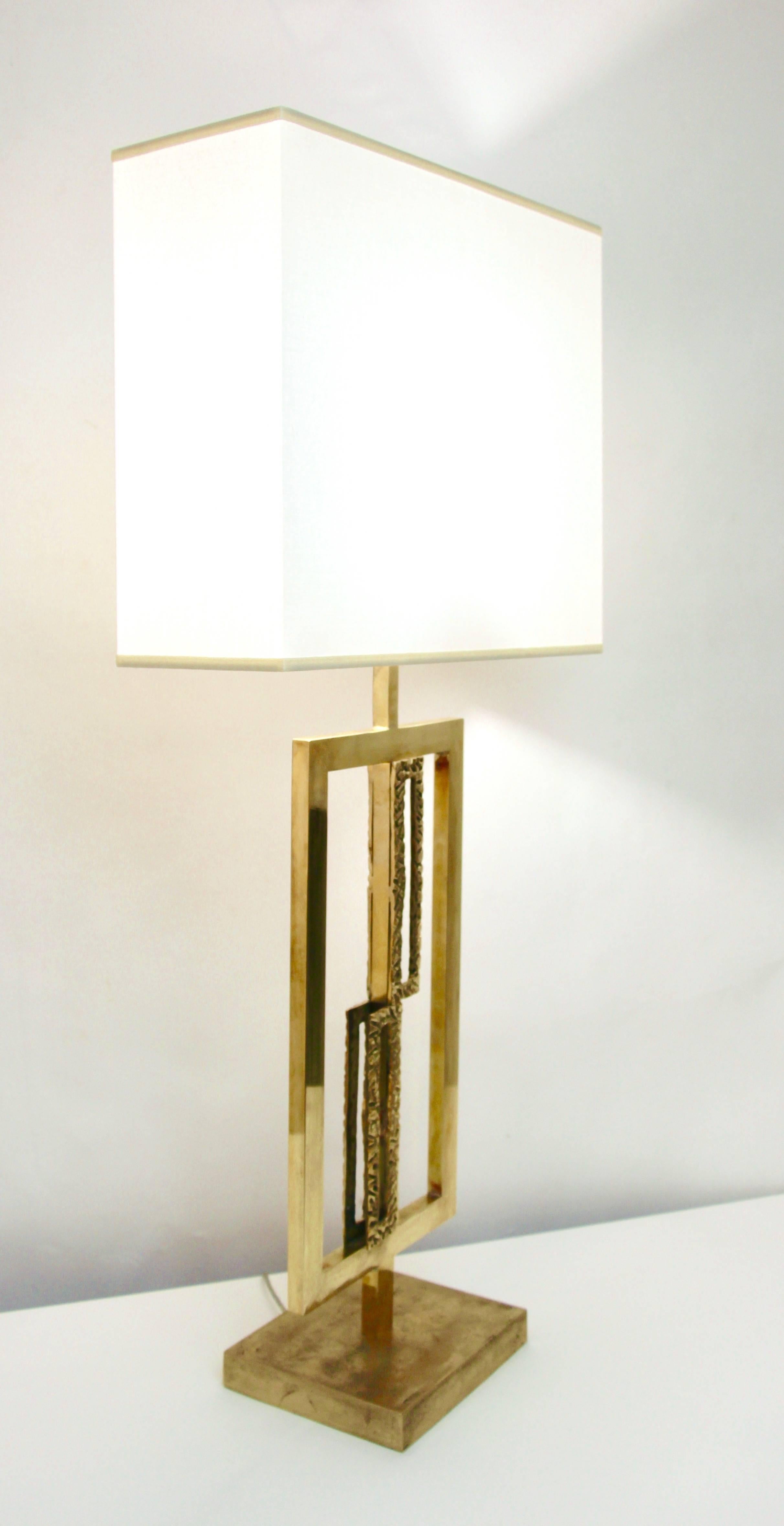 This exclusive pair of Italian pierced sculpture lamps with white shades are entirely handmade, with modern geometric design, the gold brass rectangular open frame encloses two geometrical perforated elements in cast bronze with a nice depth