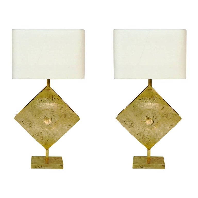 This exclusive pair of Italian sculpture custom design lamps, handcrafted for Cosulich Interiors & Antiques, presents a very interesting Brutalist cast bronze base and sail-shaped front plaque doubled by a handmade brass shield enclosing a light