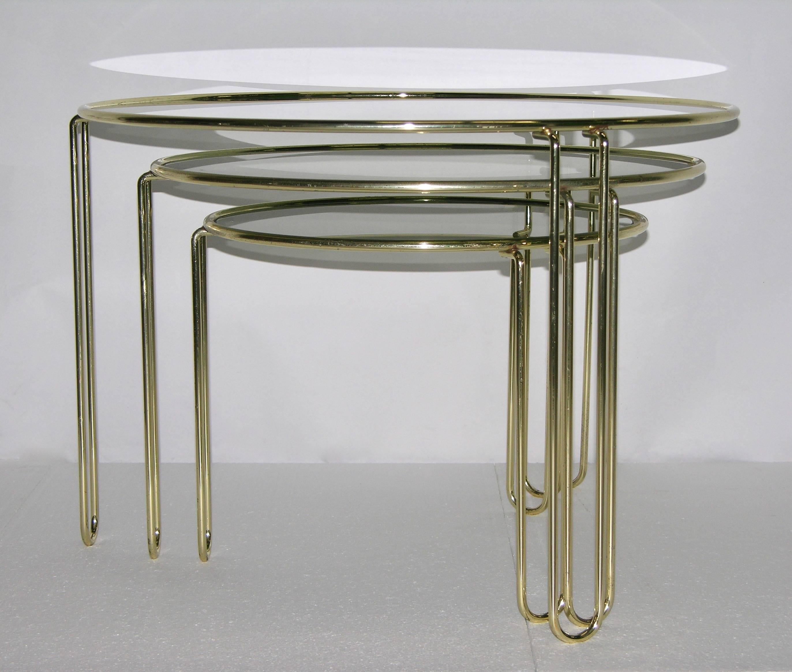 Vintage Mid-Century Modern set of very functional nesting side tables attributed to Banci, hand crafted with very clean and modern design, original smoked grey glass, the hand made gold brass structure consists of a circular pipe used in a