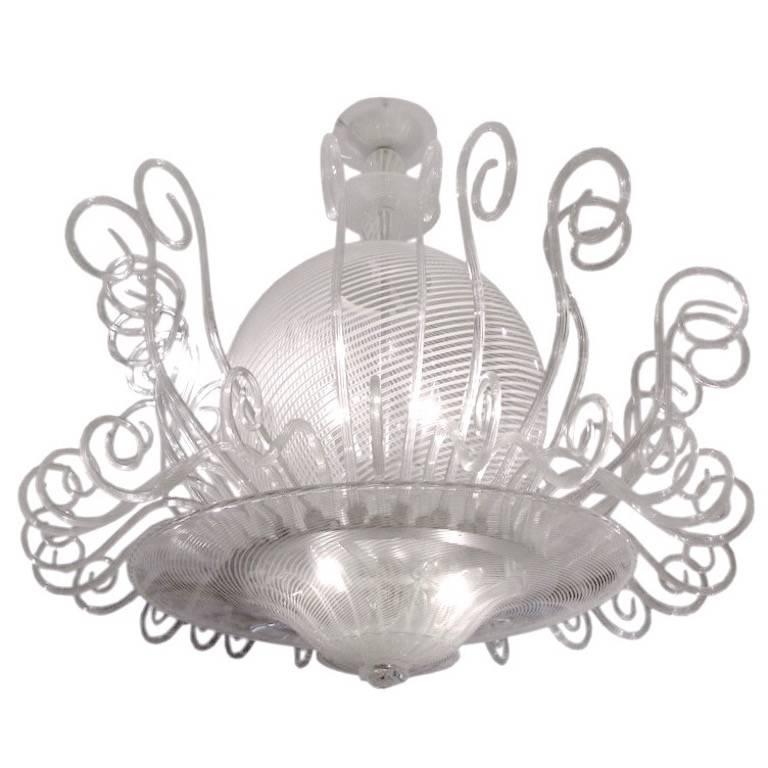 Stunning Murano glass chandelier worked with an amazing white reticello decoration, a work of art by Venini, the central huge sphere with three lights is surrounded by blown and individually crafted glass scrolls and the bowl bears also three