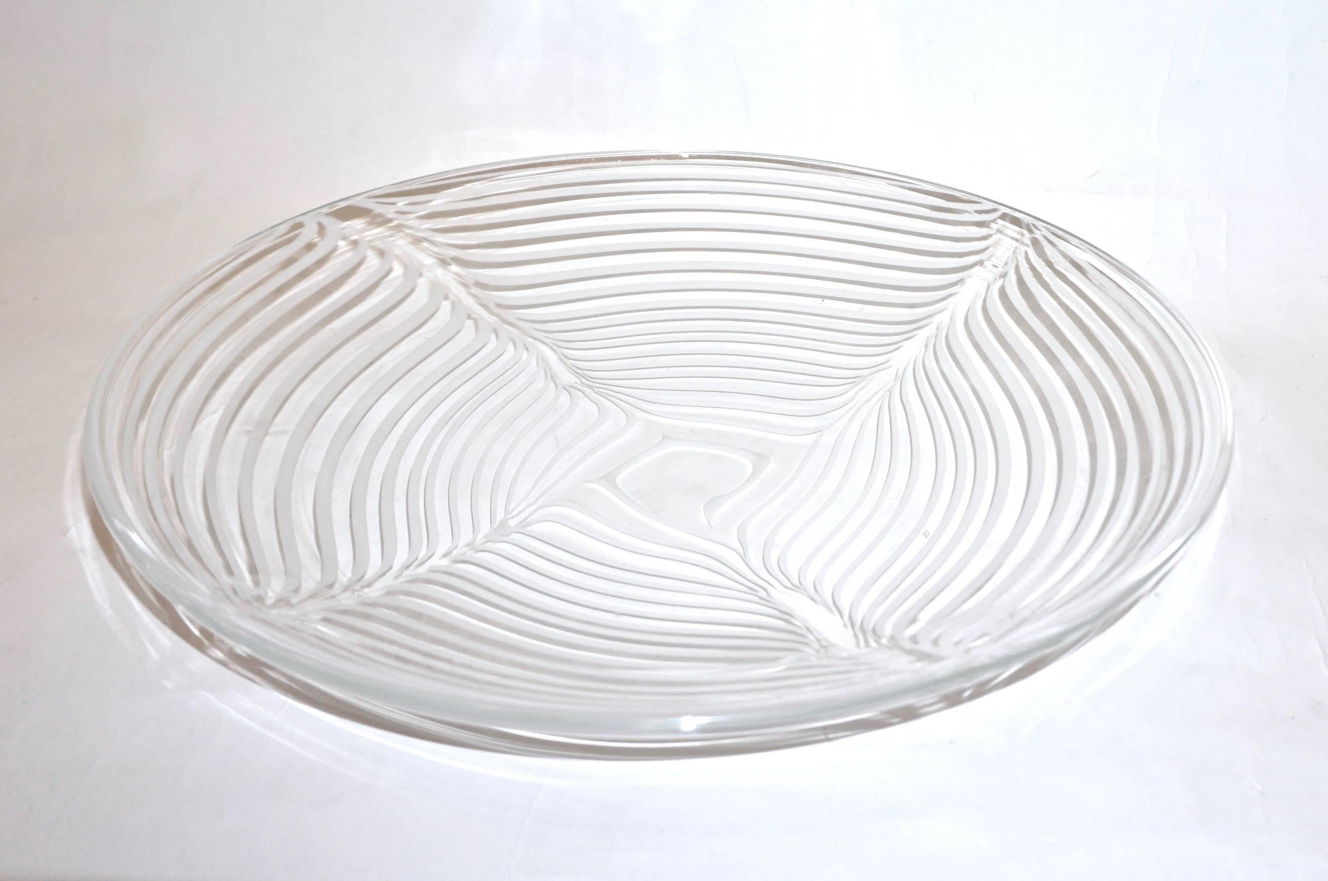1970s elegant and refined Minimalist creation signed Formia Murano, crystal clear blown Murano glass dish or centerpiece decorated with swags of white mezza filigrana that creates a very interesting design and gives uniqueness to the shape.
Can be
