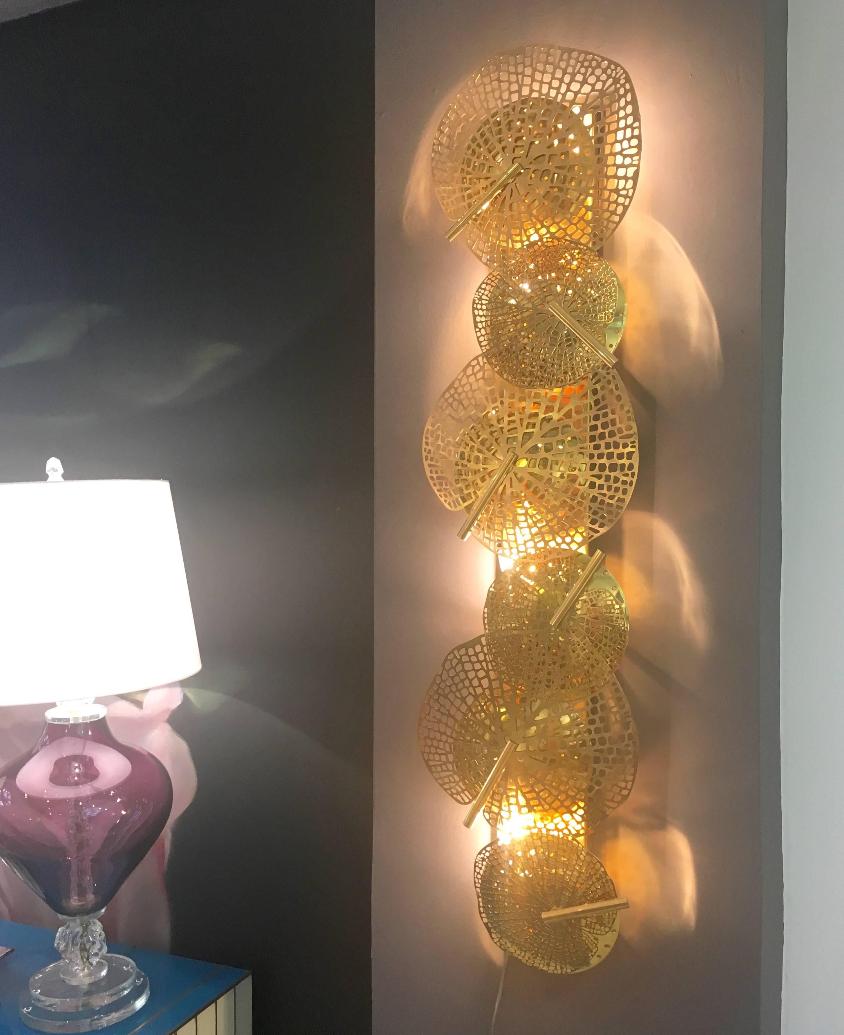 Contemporary Italian fine design pair of organic brass sculpture wall lights, entirely handmade, nature inspired Work of Art, decorated with perforated brass leaves of different sizes concealing pierced concave discs that hide a brass cone-shaped