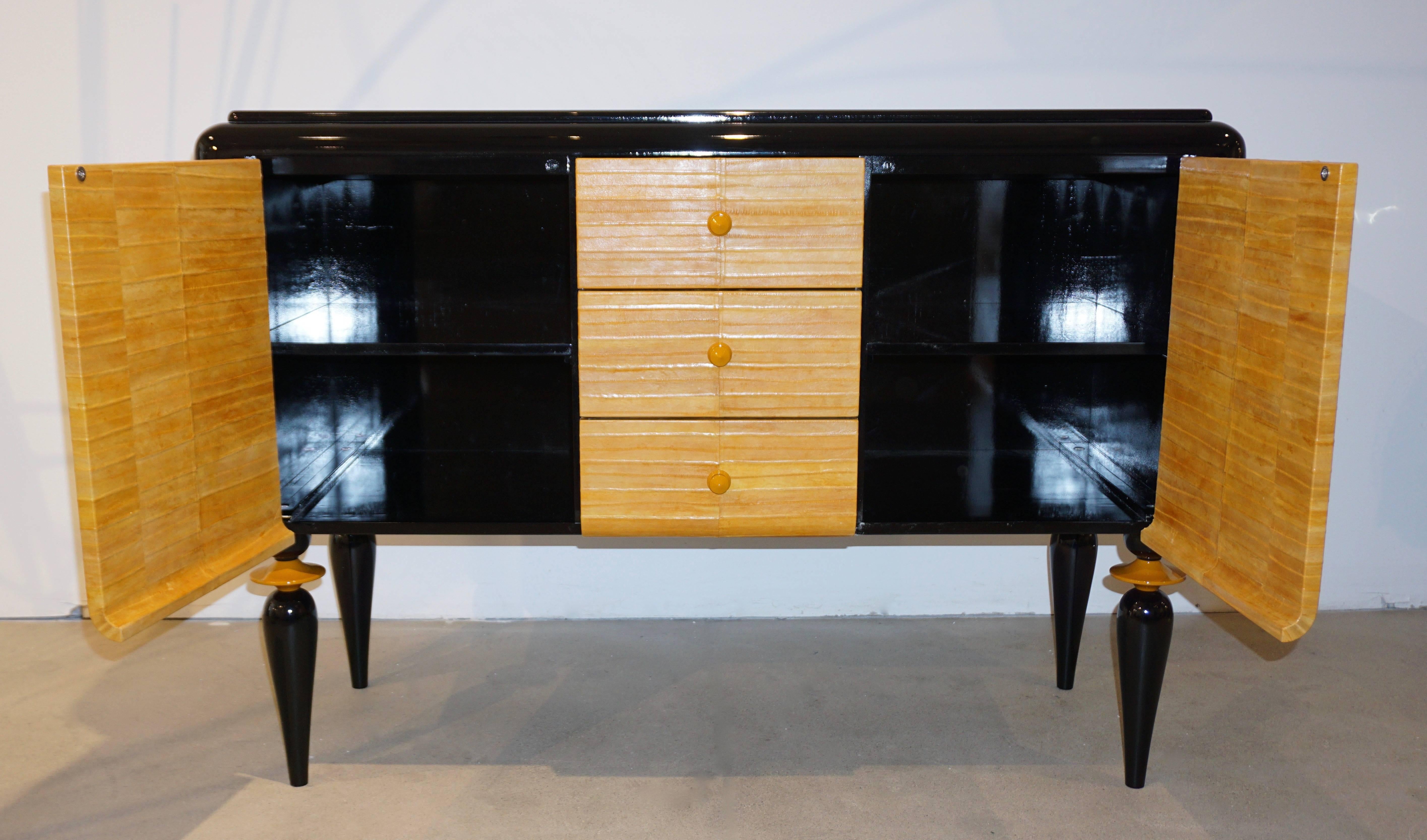 A contemporary fine design made in Italy case piece, credenza or cabinet of very high quality execution, entirely black lacquered, with stepped top surface, the front covered in yellow mustard genuine eel skin leather. The three central drawers with