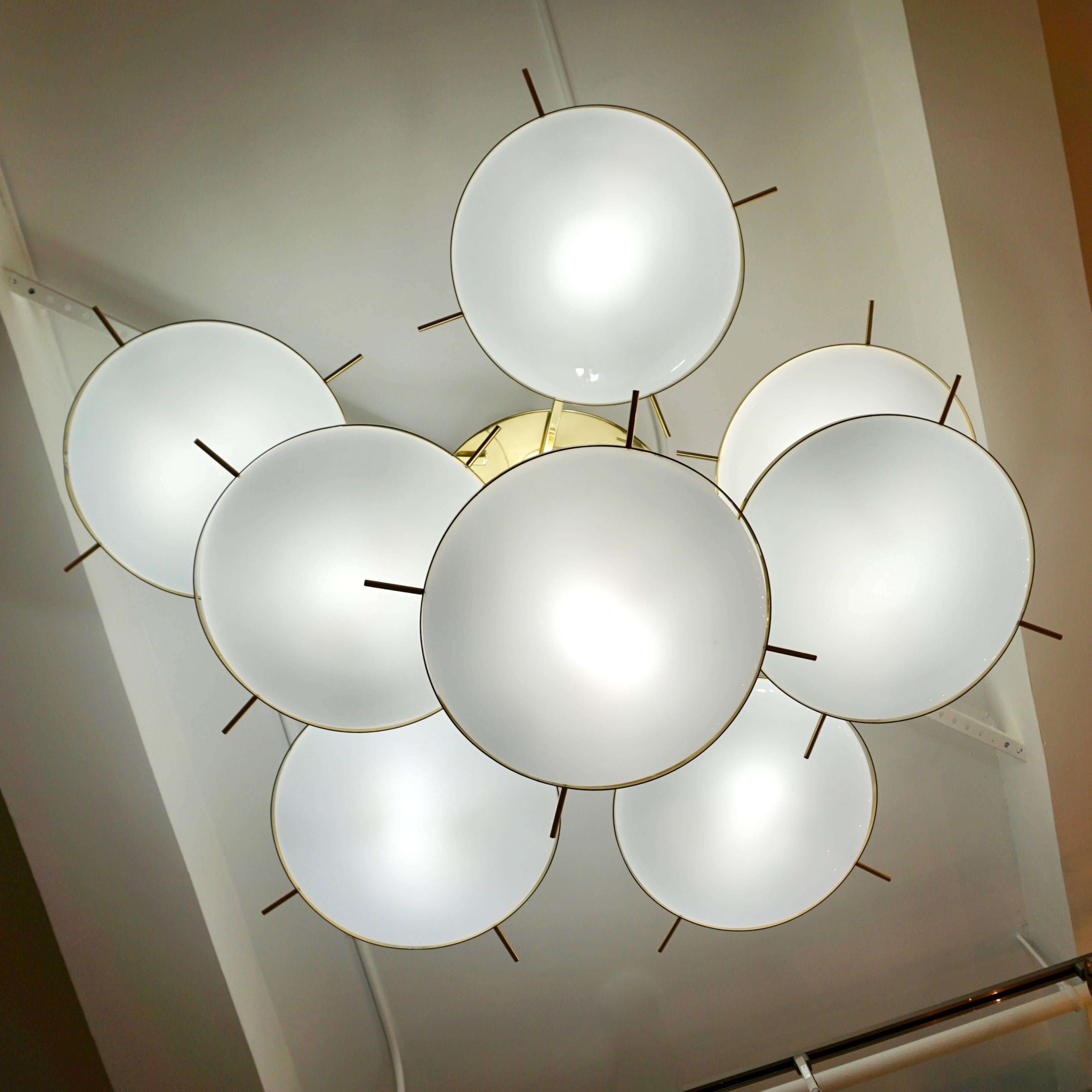 Italian fine design bespoke chandelier, entirely handmade, modern organic design, with eight round saucer-shaped shades in blown opaline white Murano glass to maximize the light, suspended on different levels like revolving planets from a