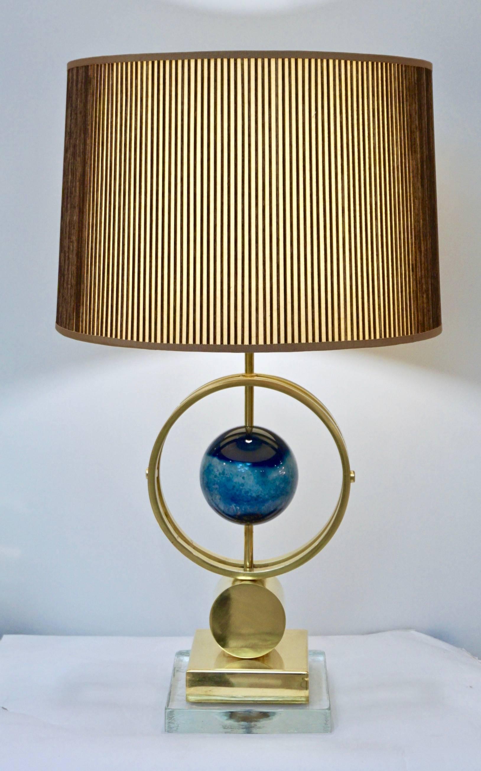 This contemporary Italian pair of organic fine design table lamps presents a high quality craftsmanship, the brass structure presents a double open ring circling a precious whole agate stone in sea aqua blue tones, polished in a solid sphere