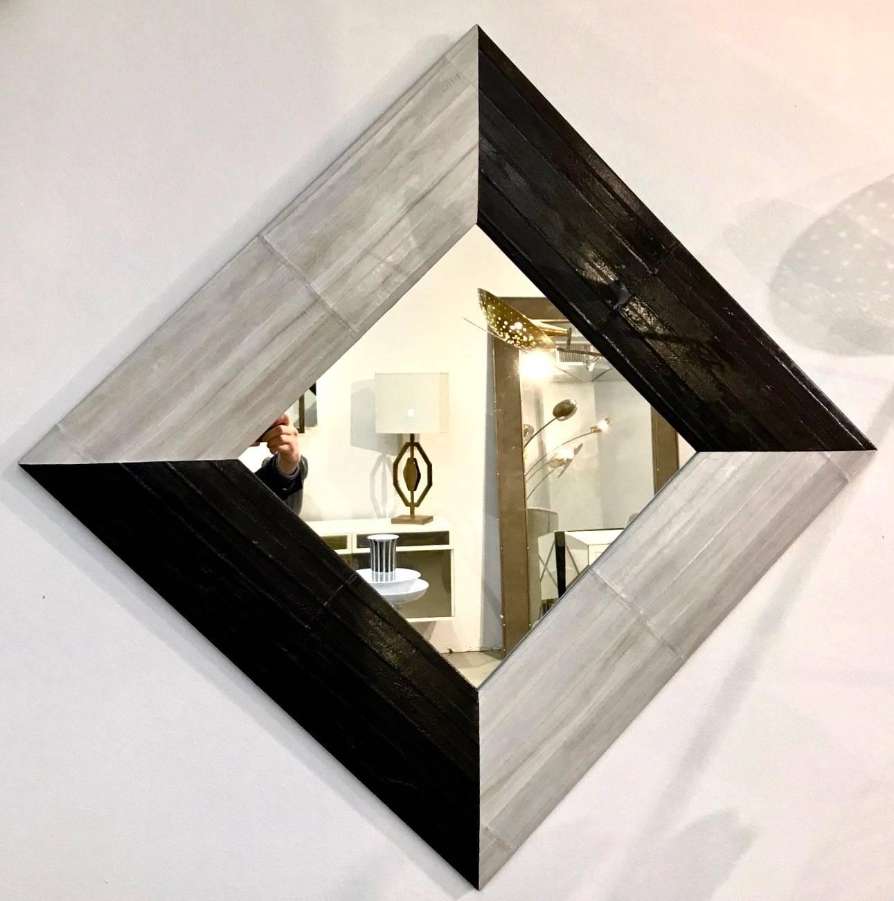 An Italian modern black and ivory grey/white square mirror, minimalist fine design, entirely handcrafted. The slightly convex wood frame is covered in a very elegant hand-stitched eel leather that gives the piece a luminous shimmer. It can be