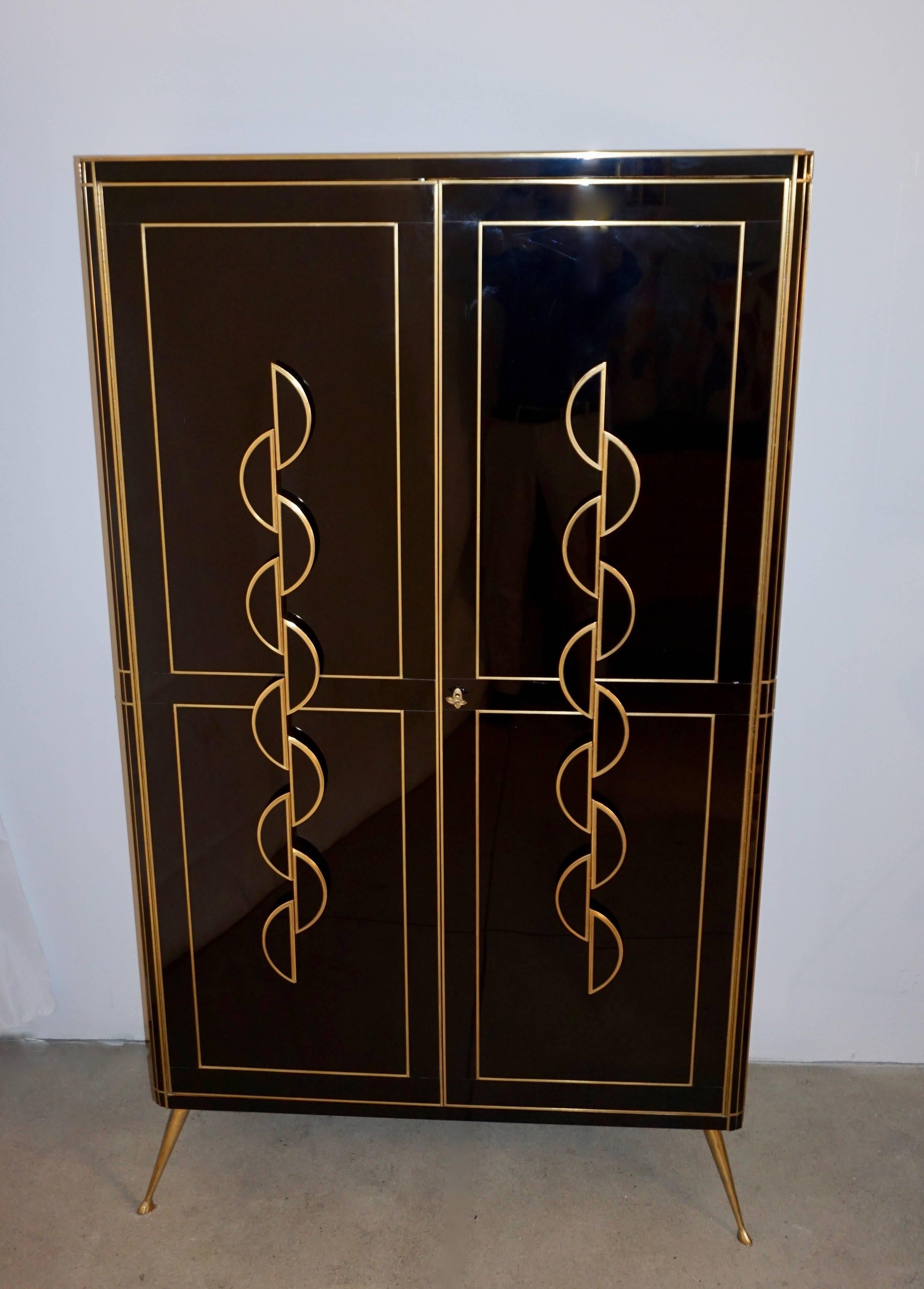 This late 1970s one-of-a kind Italian cabinet, from the North of Italy, entirely handmade, has a surround and top surface covered in black glass highlighted with brass inlays. High quality of execution and attention to details with rounded corners,