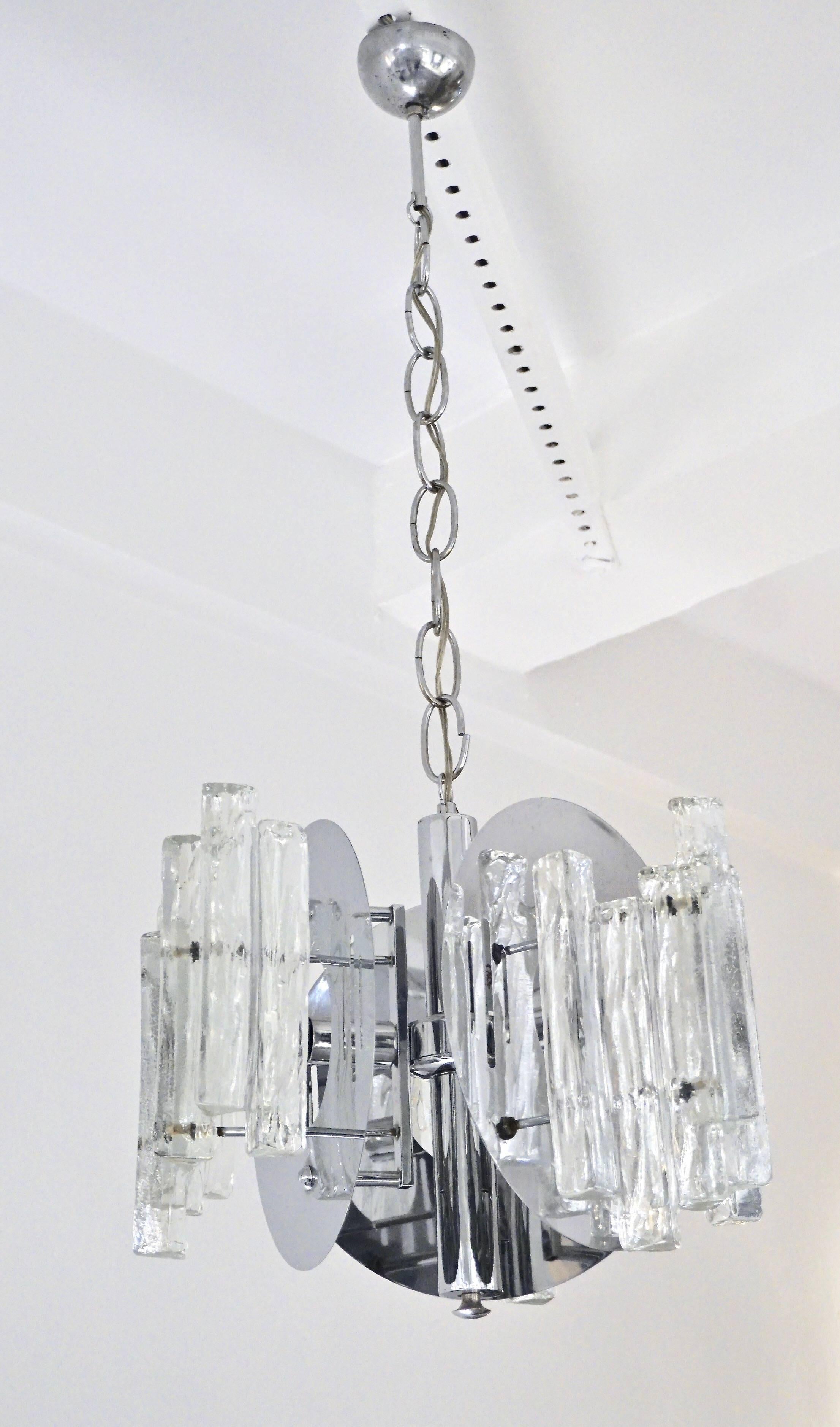 Très joli design moderniste et organique pour ce lustre de haute qualité en verre de Murano des années 1970 par Salviati : les plaques rondes en chrome manufacturé, qui sont percées pour laisser passer la lumière, sont décorées d'éléments de glaçons