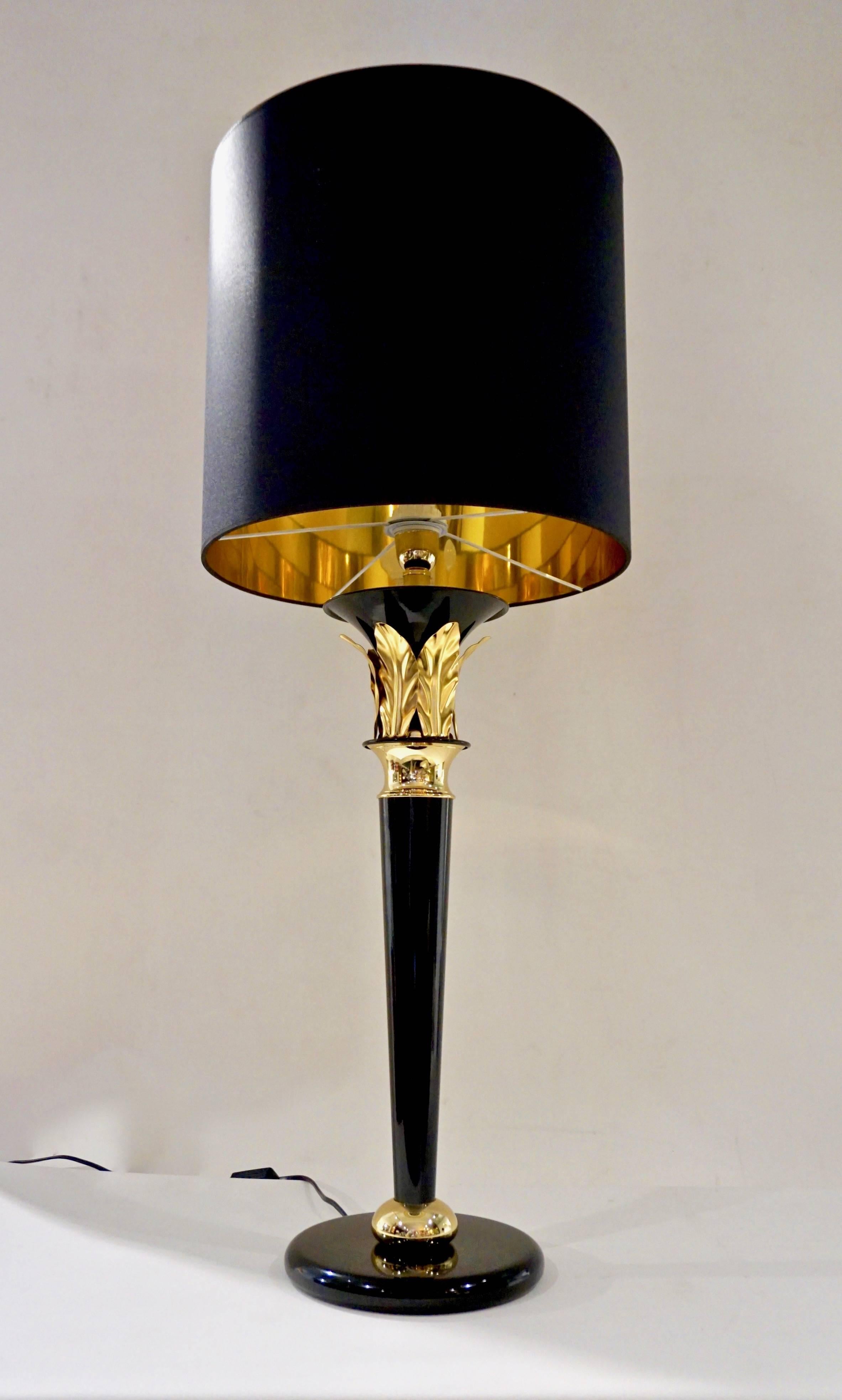A vintage pair of tall glamorous Hollywood regency design lamps, handmade in Florence - Italy in black and gold lacquered metal, high quality of execution with a sleek and modern mirror like finish, the stem as an Art Deco column is highlighted with