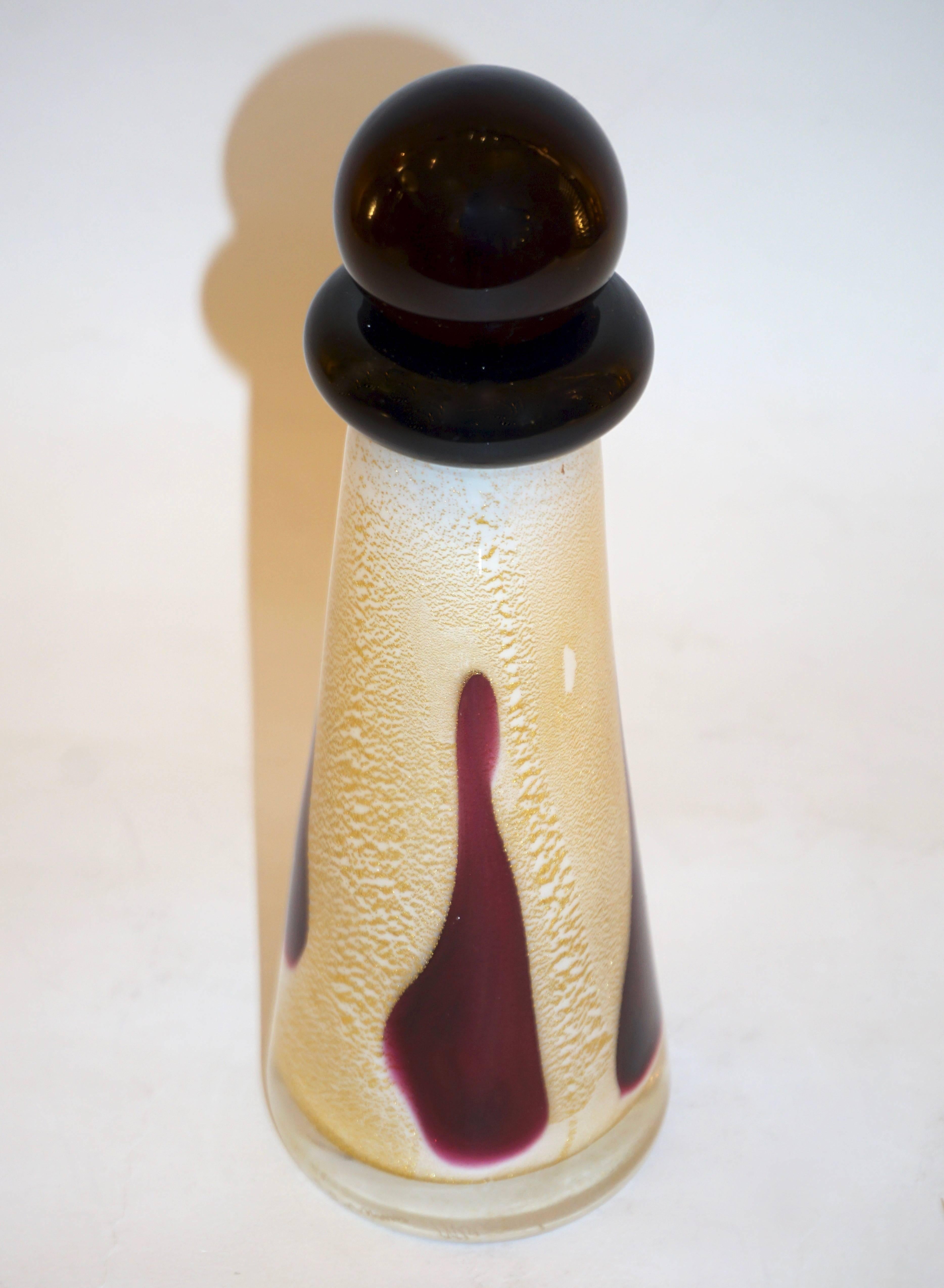 1980 very elegant organic Murano glass bottle by Formia, signed. The body is worked with expanded 24kt gold leaf in pearl ivory Murano glass encased in crystal clear glass, decorated with burgundy wine red Murrine and highlighted by a black glass