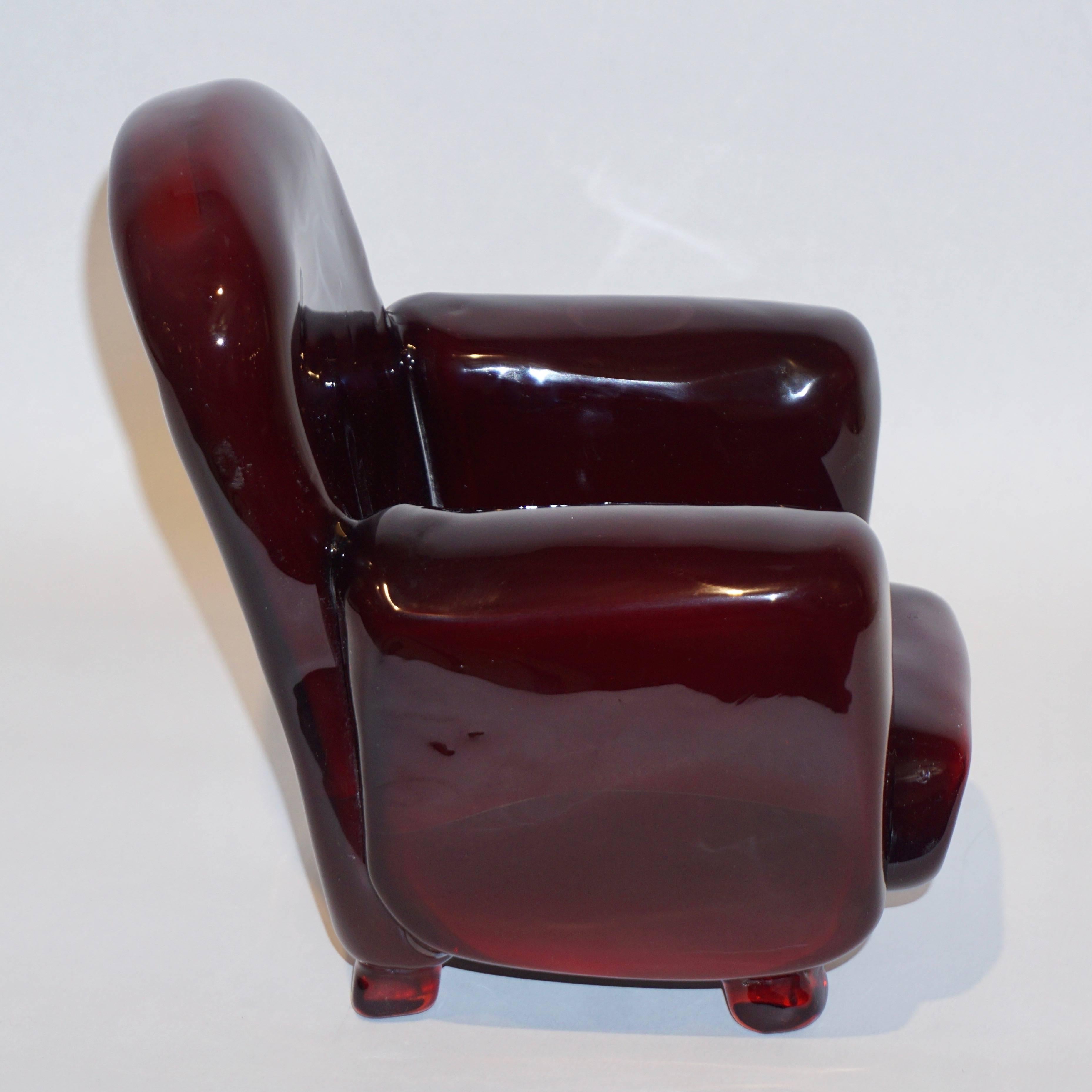 This delightful armchair in miniature size is a vintage organic Work of Art, sculpture in blown Murano art glass, signed by Pino Signoretto, in an attractive wine red color. A charming object, nicely detailed. One arm presents a circle visible in