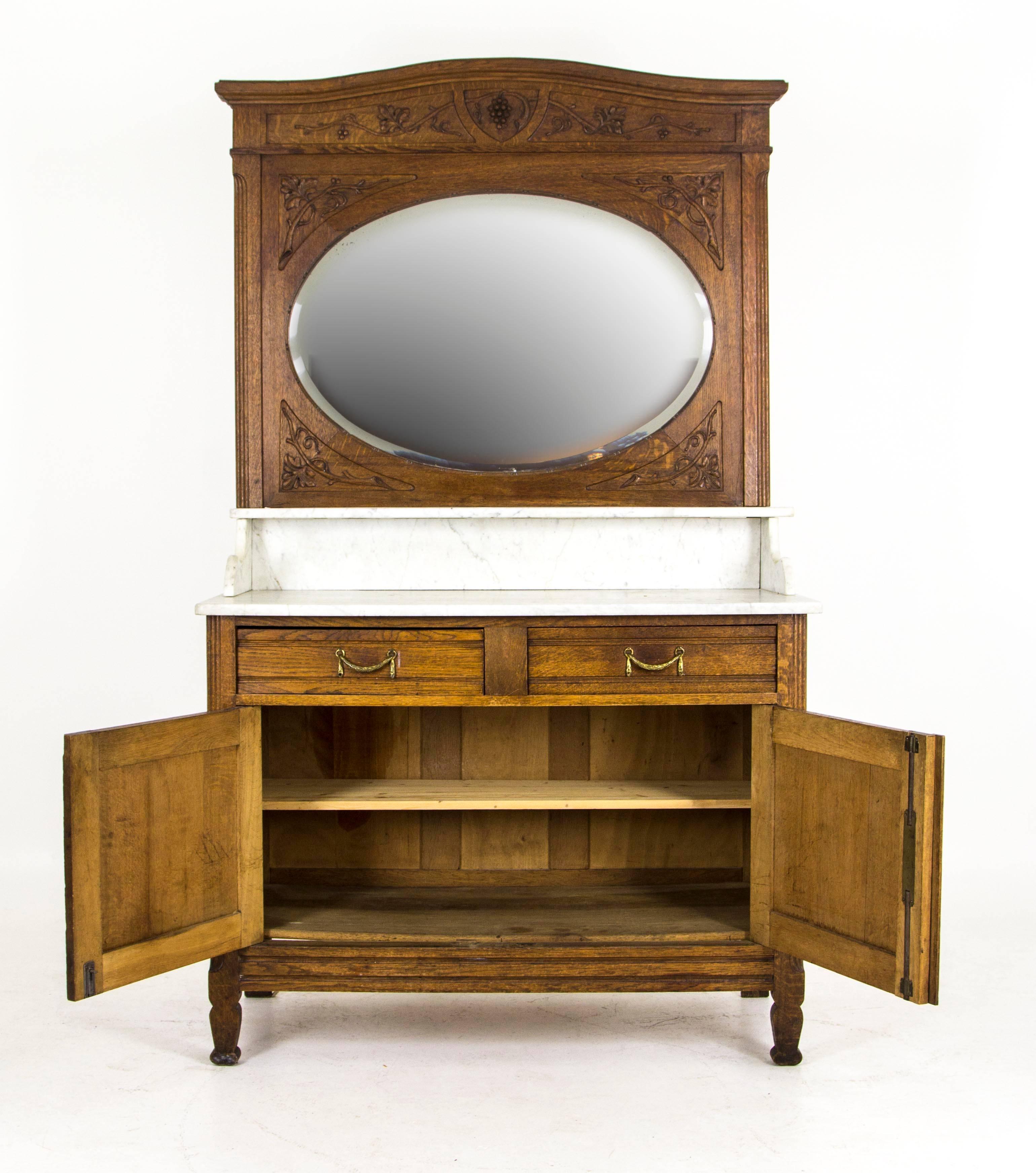 France, 1880
Original finish
Solid oak construction
Carved oak back with oval bevelled mirror
Marble top with hairline crack
Two dovetailed drawers with original brass hardware
Two carved doors open to reveal single shelf
Ending on shaped