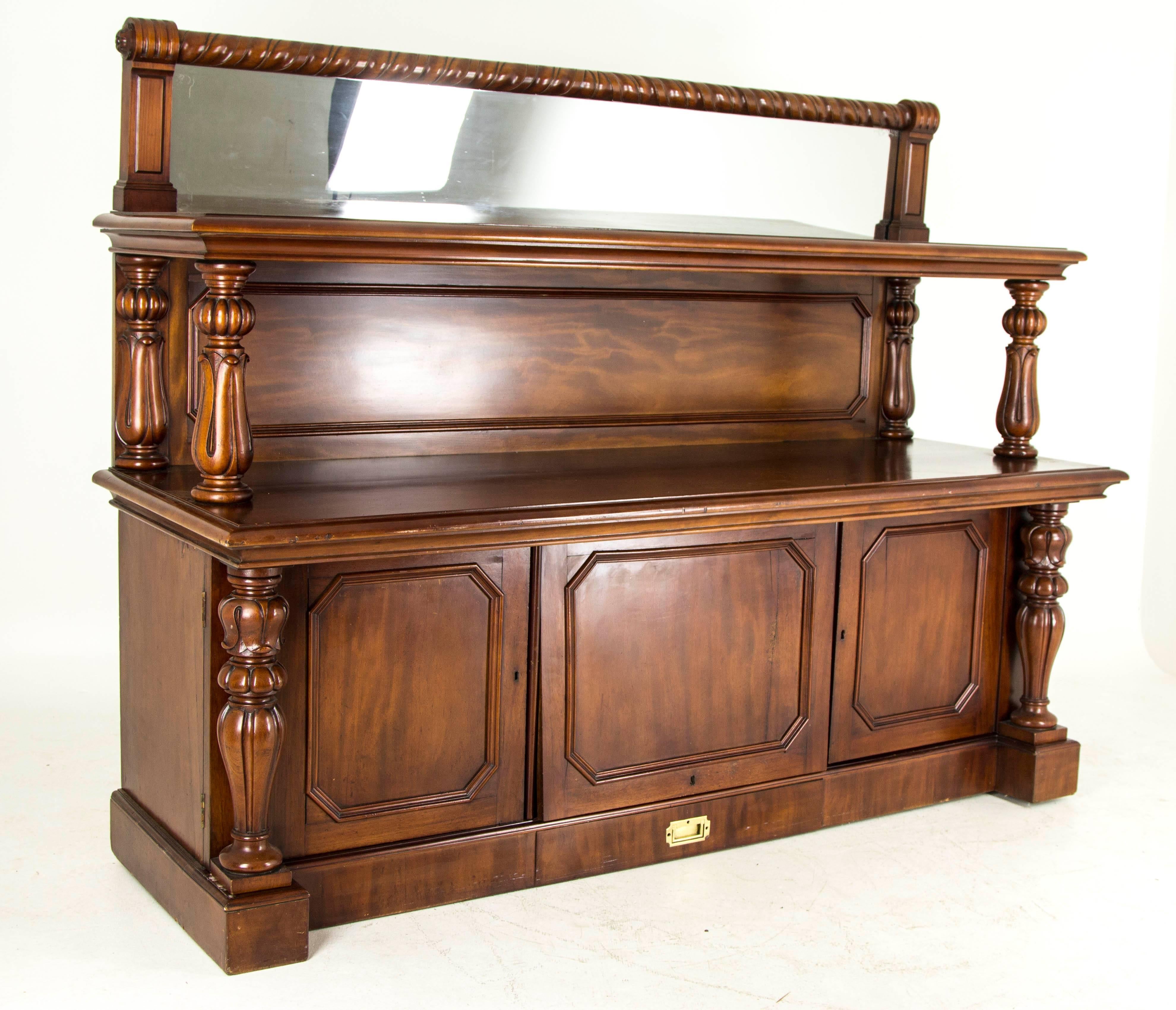 Scotland 
1870
Solid Walnut and mahogany veneers
Original finish
Mirrored back with top shelf
Four pillars below with large top
Three cupboards below opening to reveal central bottle holder flanked by two cupboards
Single brass handled drawers