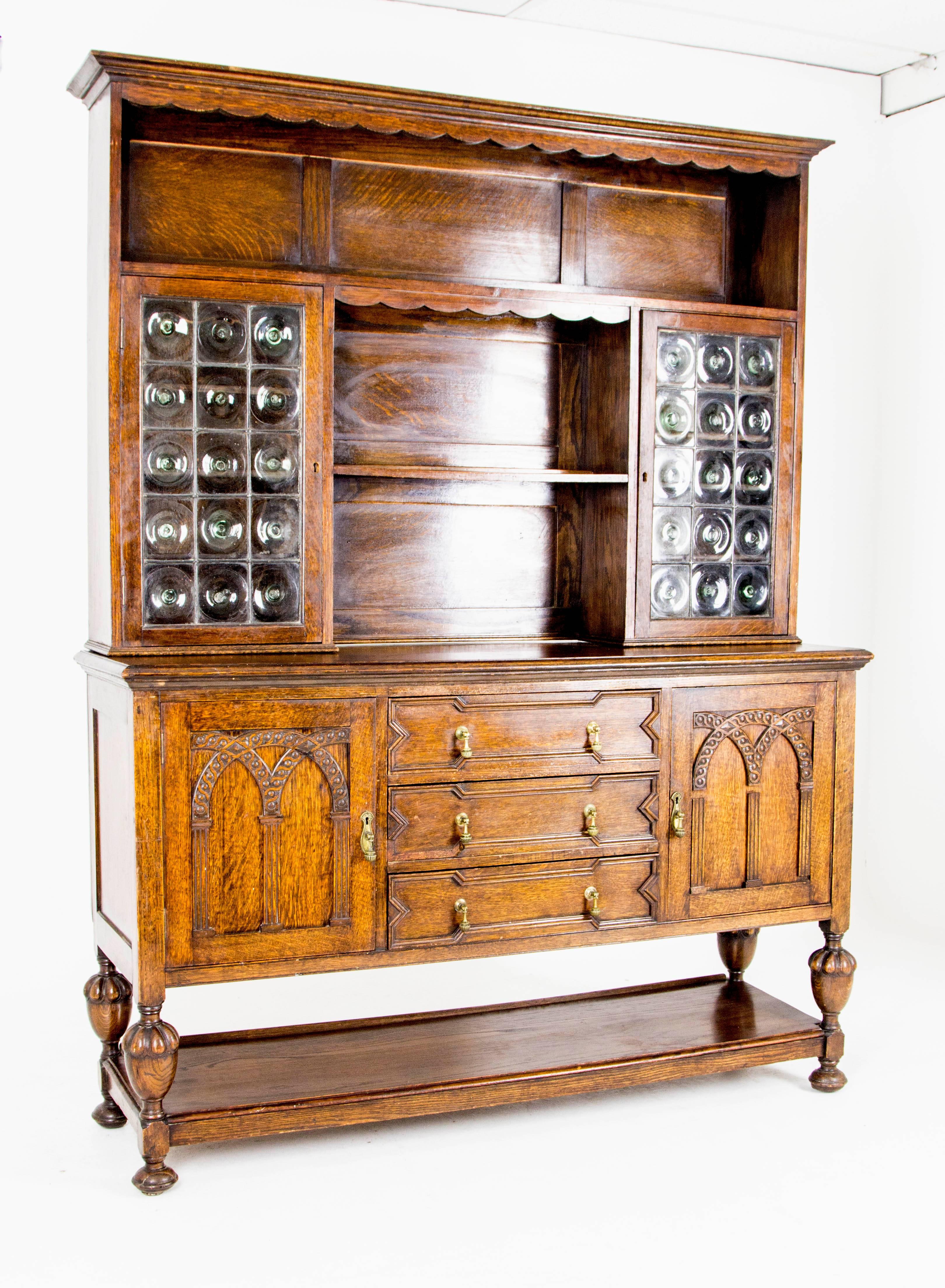 Scotland
1910
Solid oak construction
Original finish
Plate rack above with central plate rack below
Flanked by shelved cupboards with bullseye glass doors
Three central drawers flanked by shelved cupboards
Ending on bulbous legs connected by open