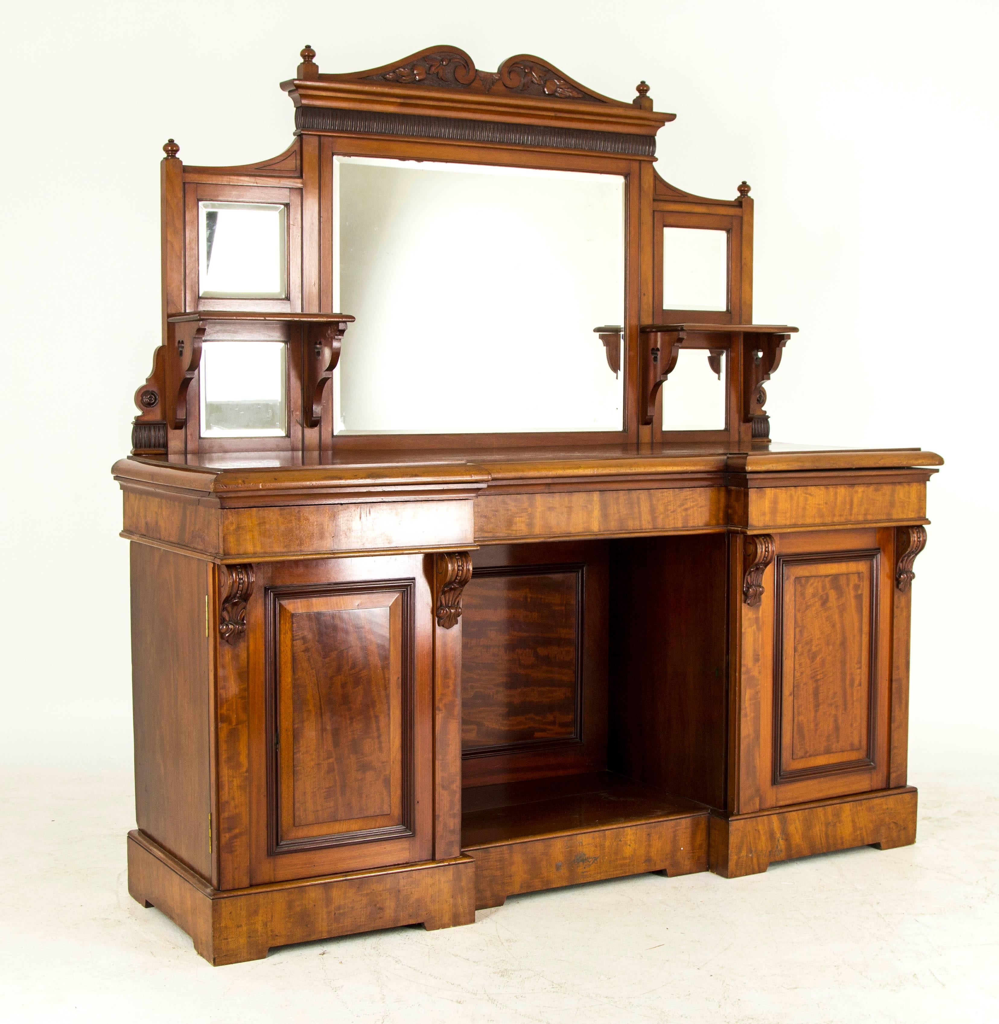 Scotland 
1870
Solid Walnut and mahogany veneers
Original finish
Carved pediment above
Large central beveled mirror
Flanked by two carved shelves with beveled mirror above and below
Inverted top above three drawers
Two cupboards below with fitted