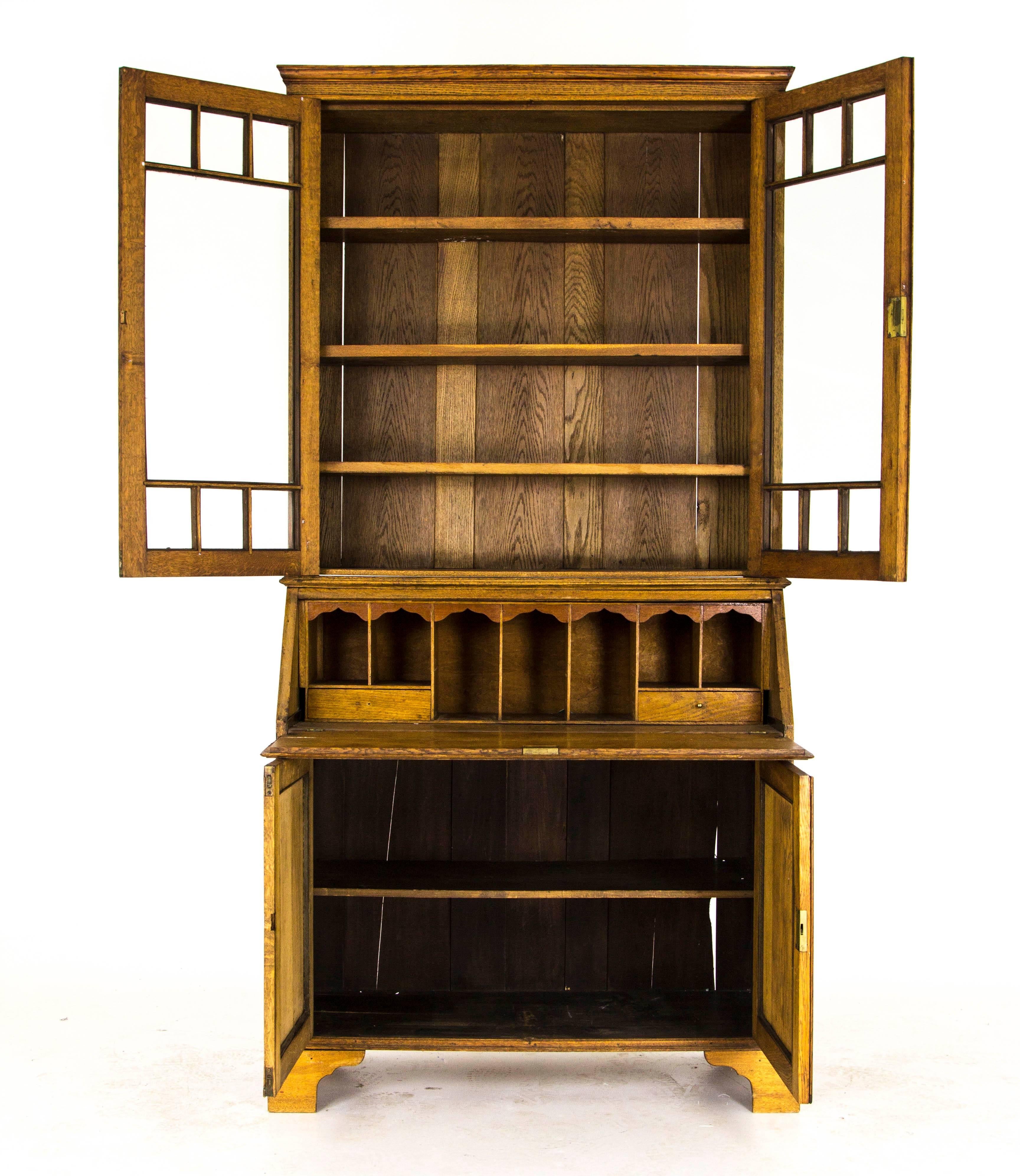 Scotland 
1910
Solid oak construction
Original finish
Two bubble glass doors
Three adjustable shelves
A full front that opens to reveal a fitted interior with two small drawers
Two-door cupboard below with a single shelf interior
Ends on