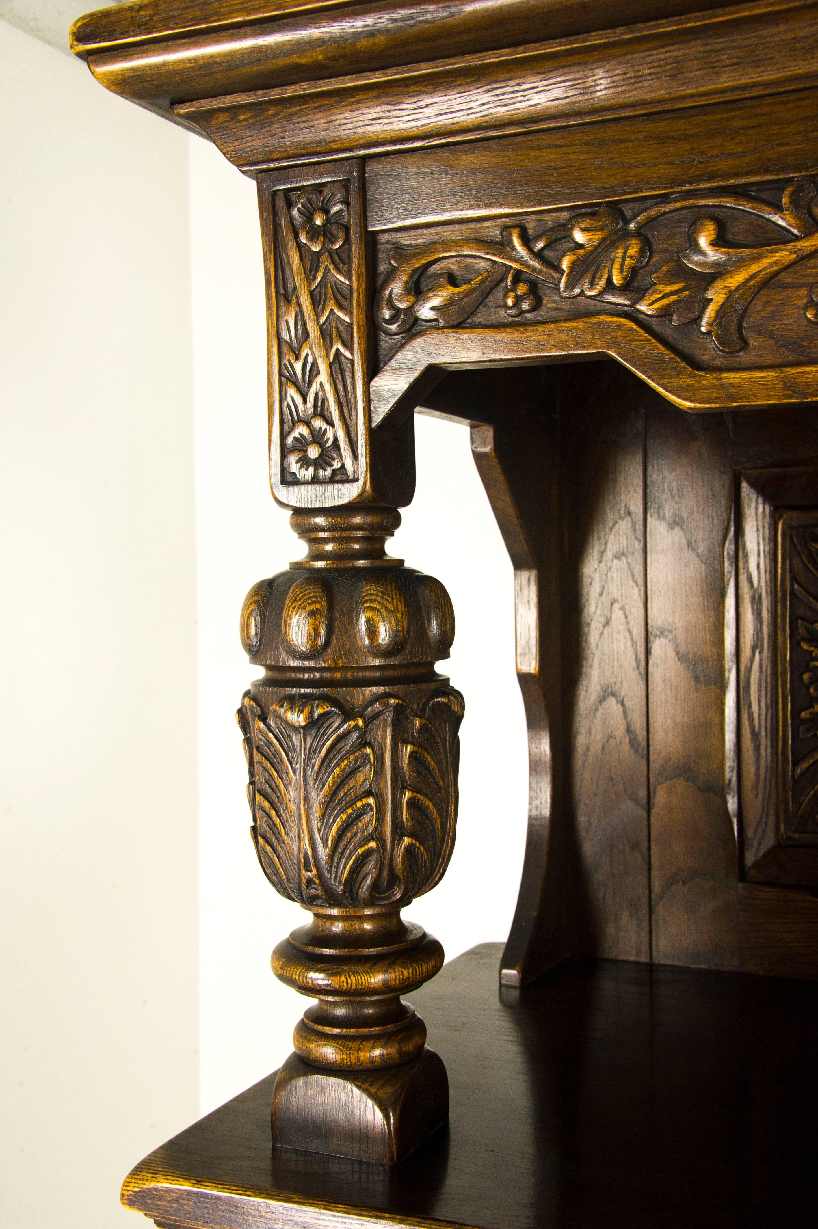 Oak court cupboard carved oak sideboard Krug and Sons, Canada, 1950s

Canada, 1950s
Solid oak construction
Original finish
Uppers section having an overhanging cornice
Three panelled cared oak back
Supported by large bulbous supports
Three carved