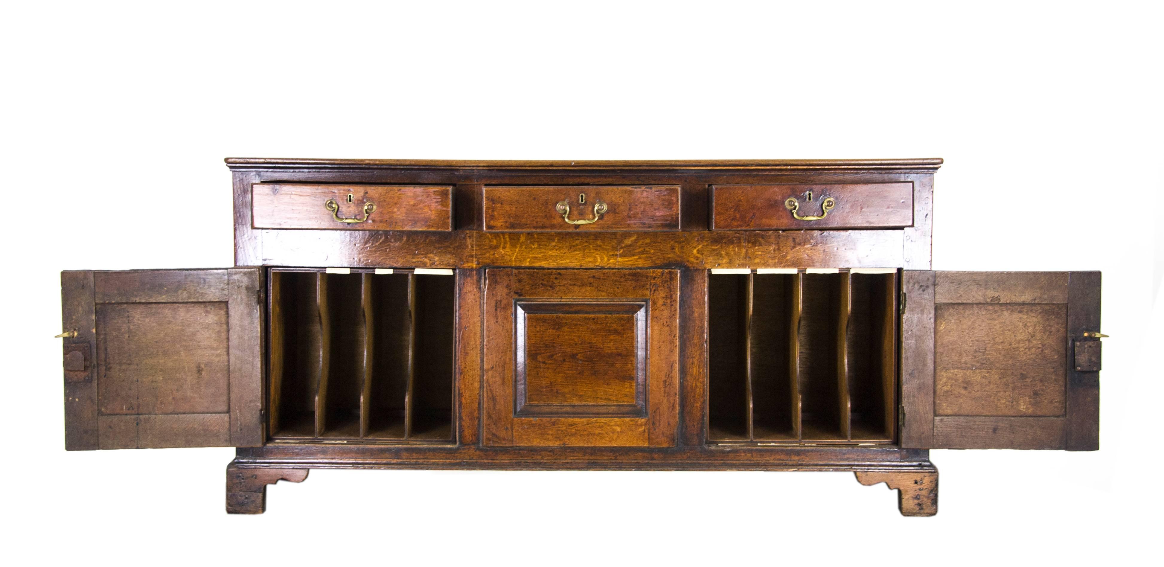 Antique oak sideboard oak dresser, England, 18th century

England, 18th century, 
Solid oak construction
Original finish
Rectangular top with three drawers below
Brass hardware
Two rectangular paneled doors
Flanking a central panel