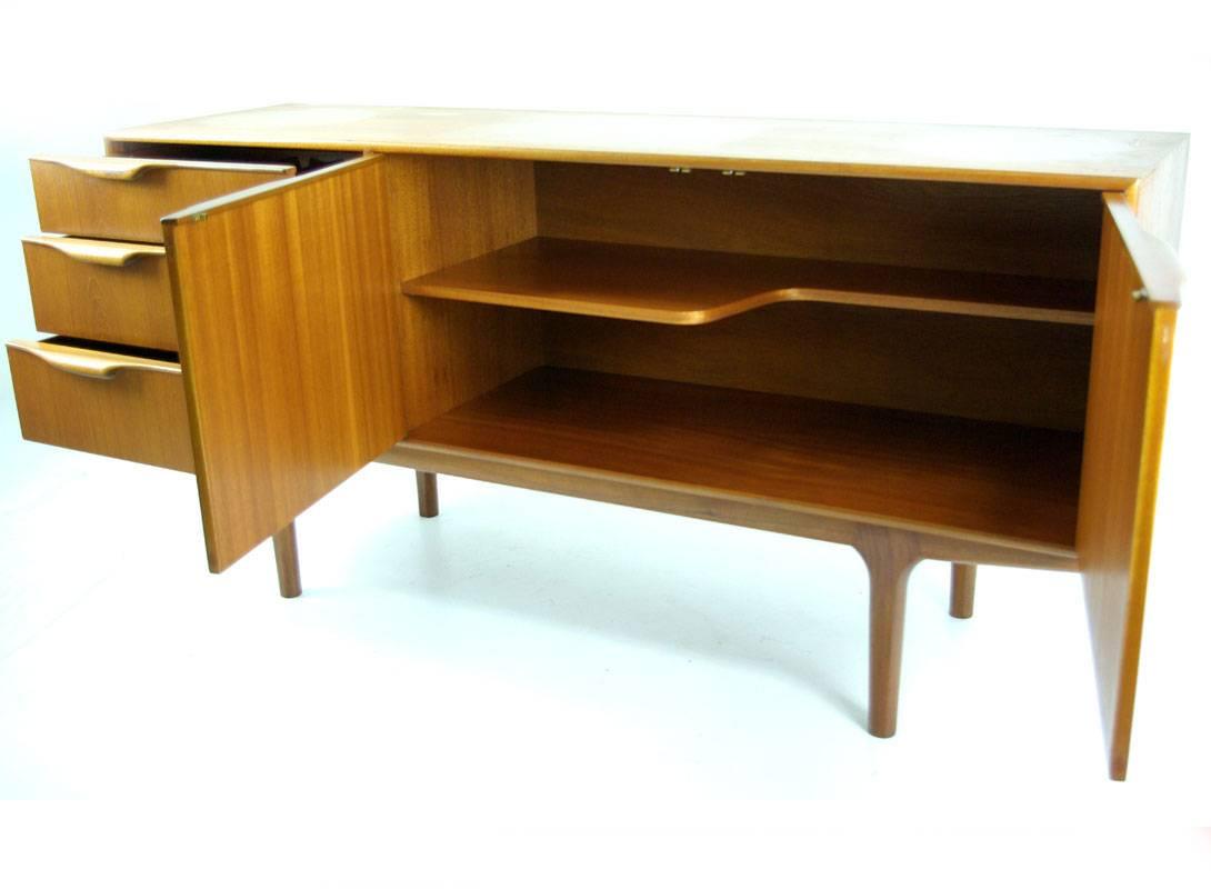 Scotland, 
1960.
Excellent Mid-Century detailing.
Minor wear to sculptured handles.
Two right hand doors open to reveal single shaped shelf.
Left side consists of three drawers.
Top drawer is felt lined cutlery drawer with McIntosh