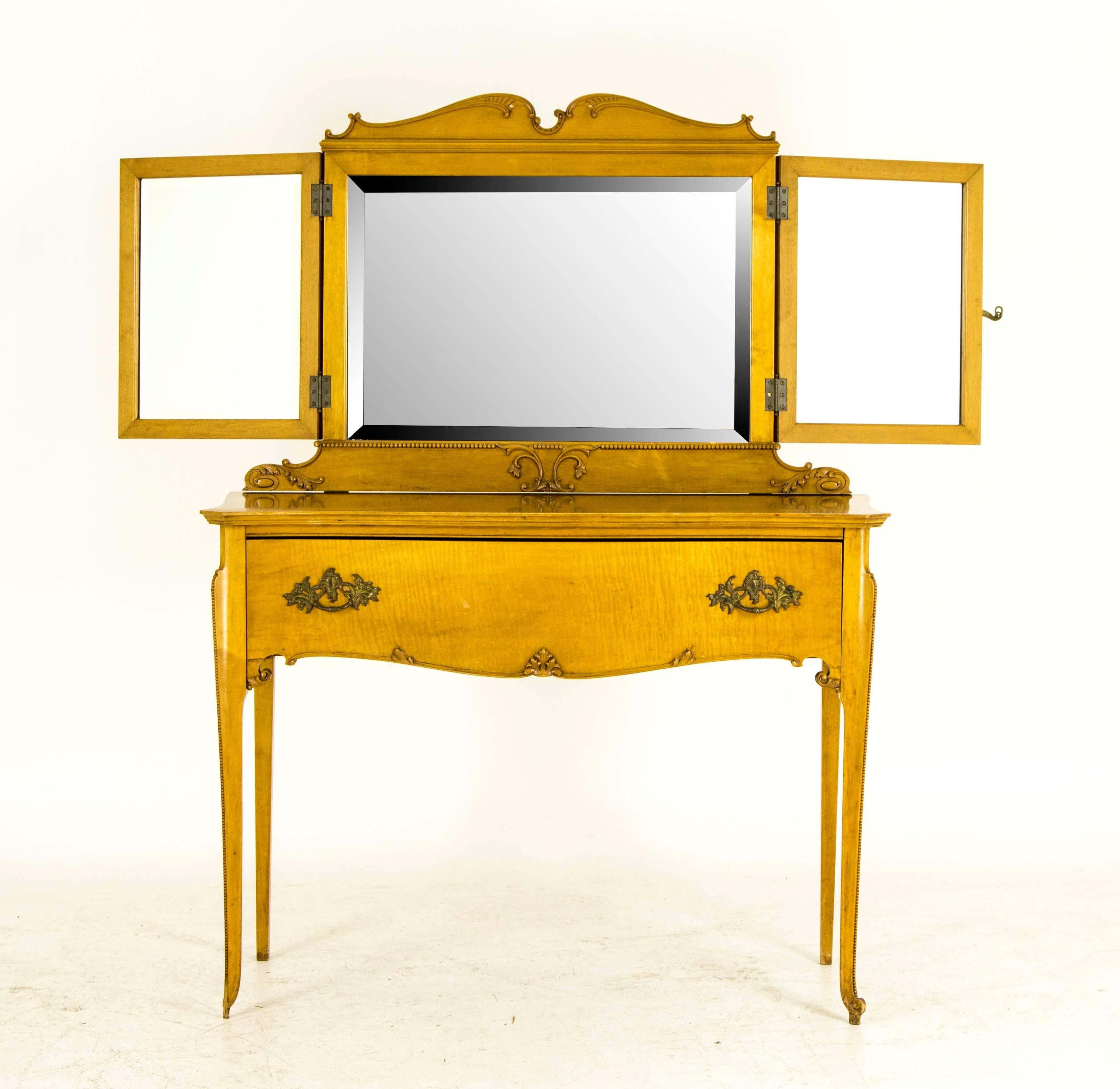 Solid tiger maple and veneers
Original finish
Applied carvings to the front of the closed top with brass fittings and clasp
Opens to reveal three framed beveled mirrors
Single long dovetailed drawer with original brass handle
Ending on tall