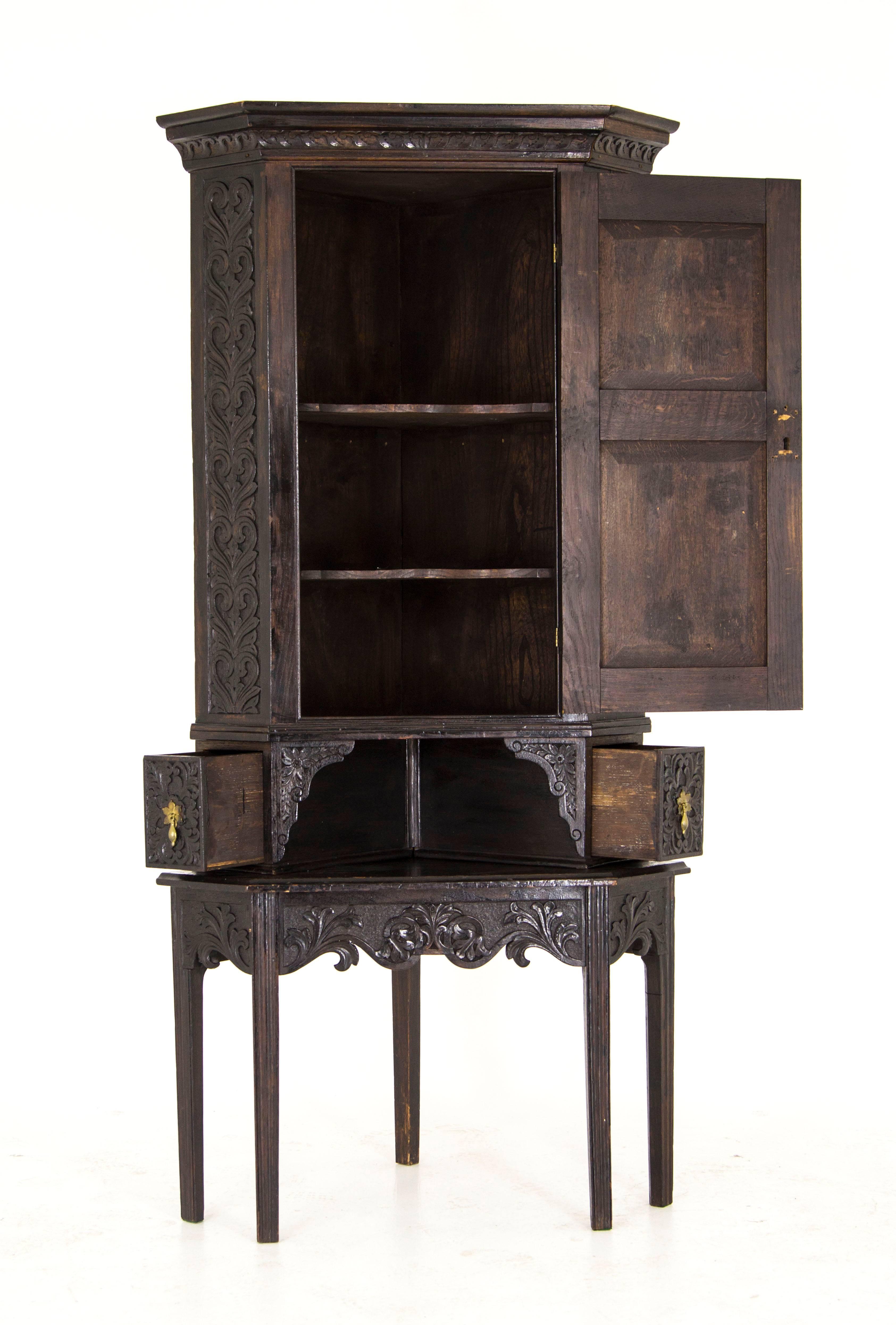 Scotland, 1830
Carved cornice above
Solid carved oak panels
Single carved door has original brass hinges
Carved sides 
Door opens to reveal two exterior shelves
Two small carved drawers on the base of the cabinet.
Sitting on a carved stand