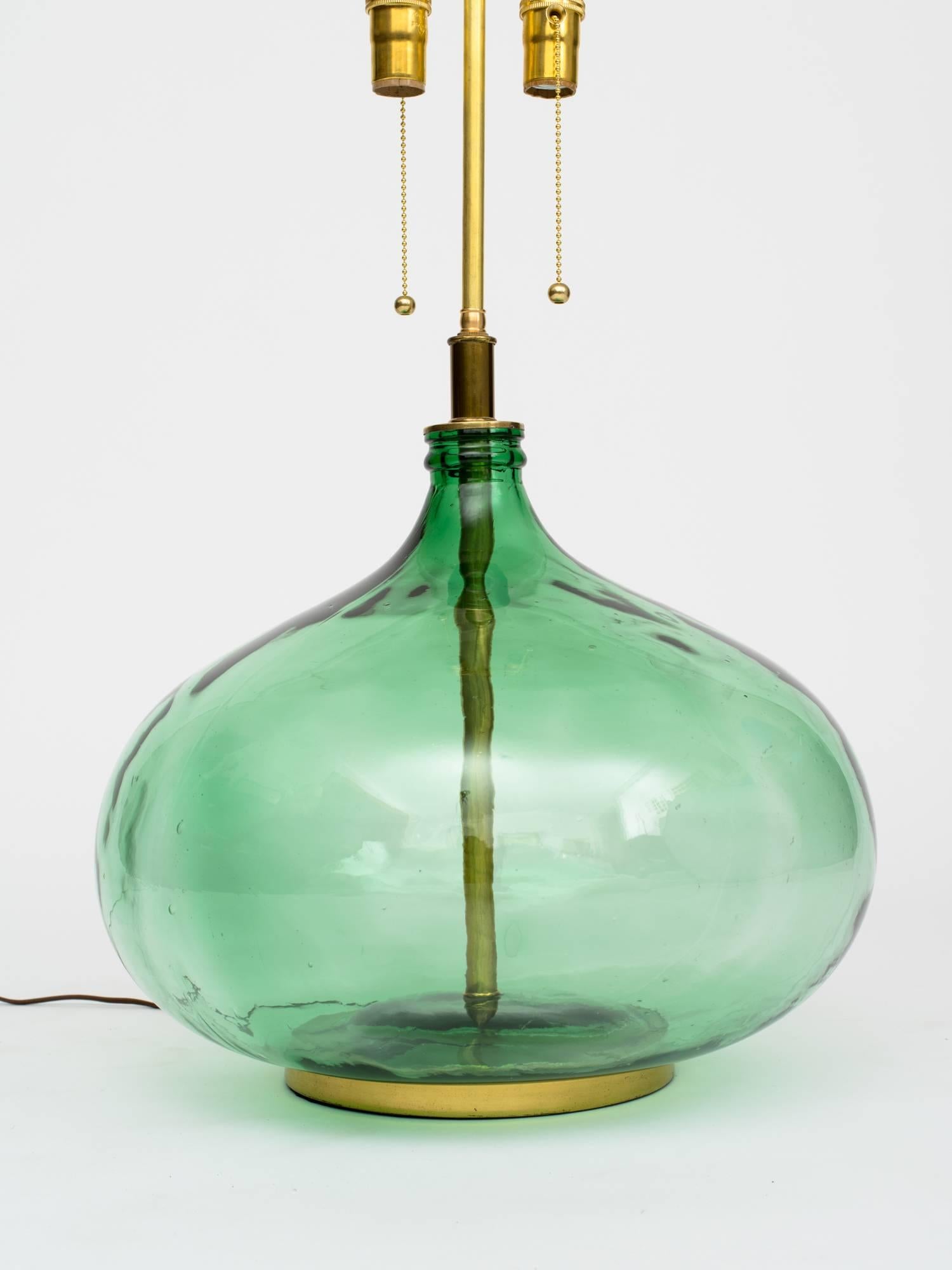 Pair of 1960s monumental green glass bottle lamps. Rewired with solid brass hardware with double sockets and pull chains.