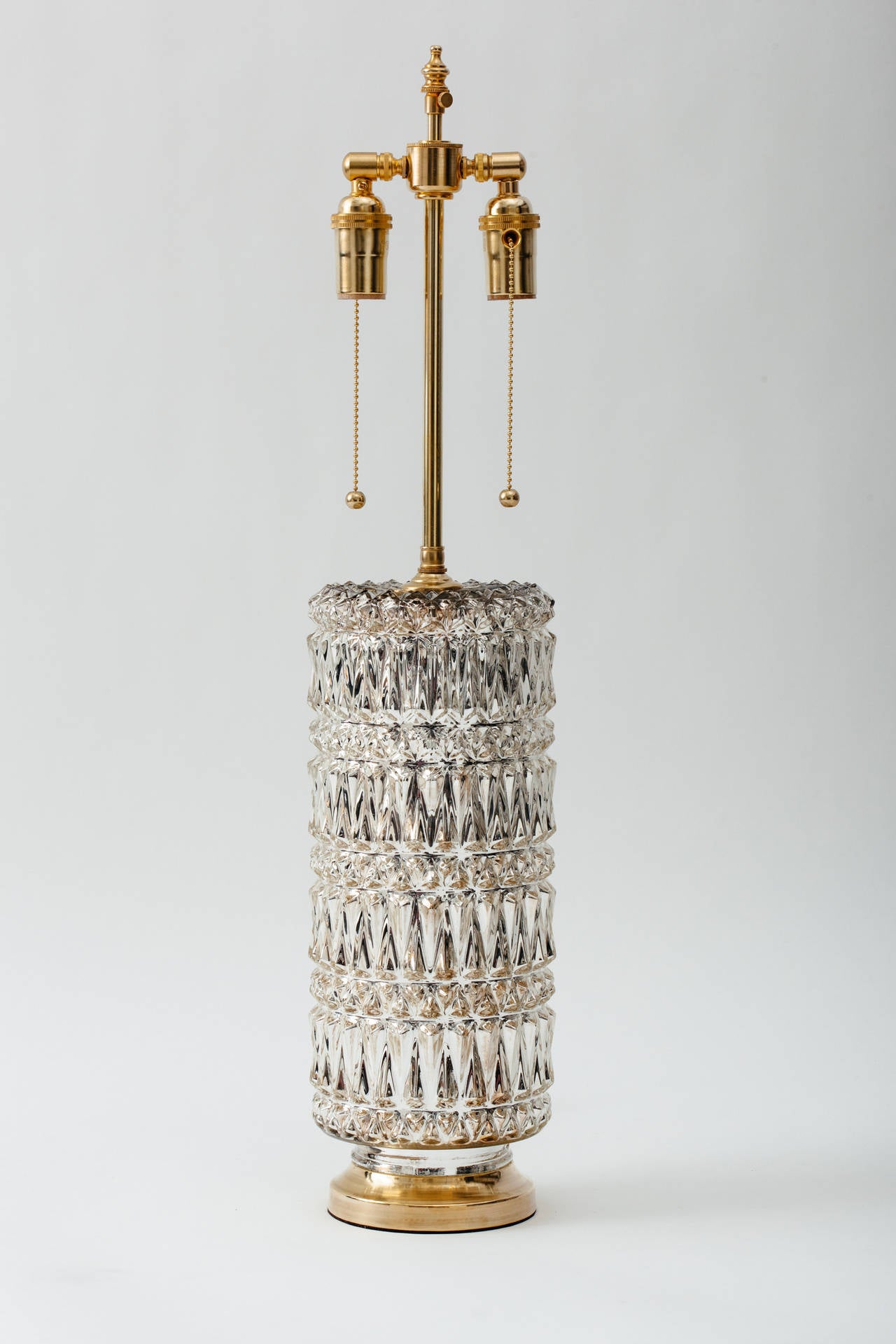 A pair of lustrous Hollywood Regency diamond patterned mercury glass lamps with brass bases. Double socketed solid brass hardware with pull chains. 100 watts max per socket, circa 1970s.