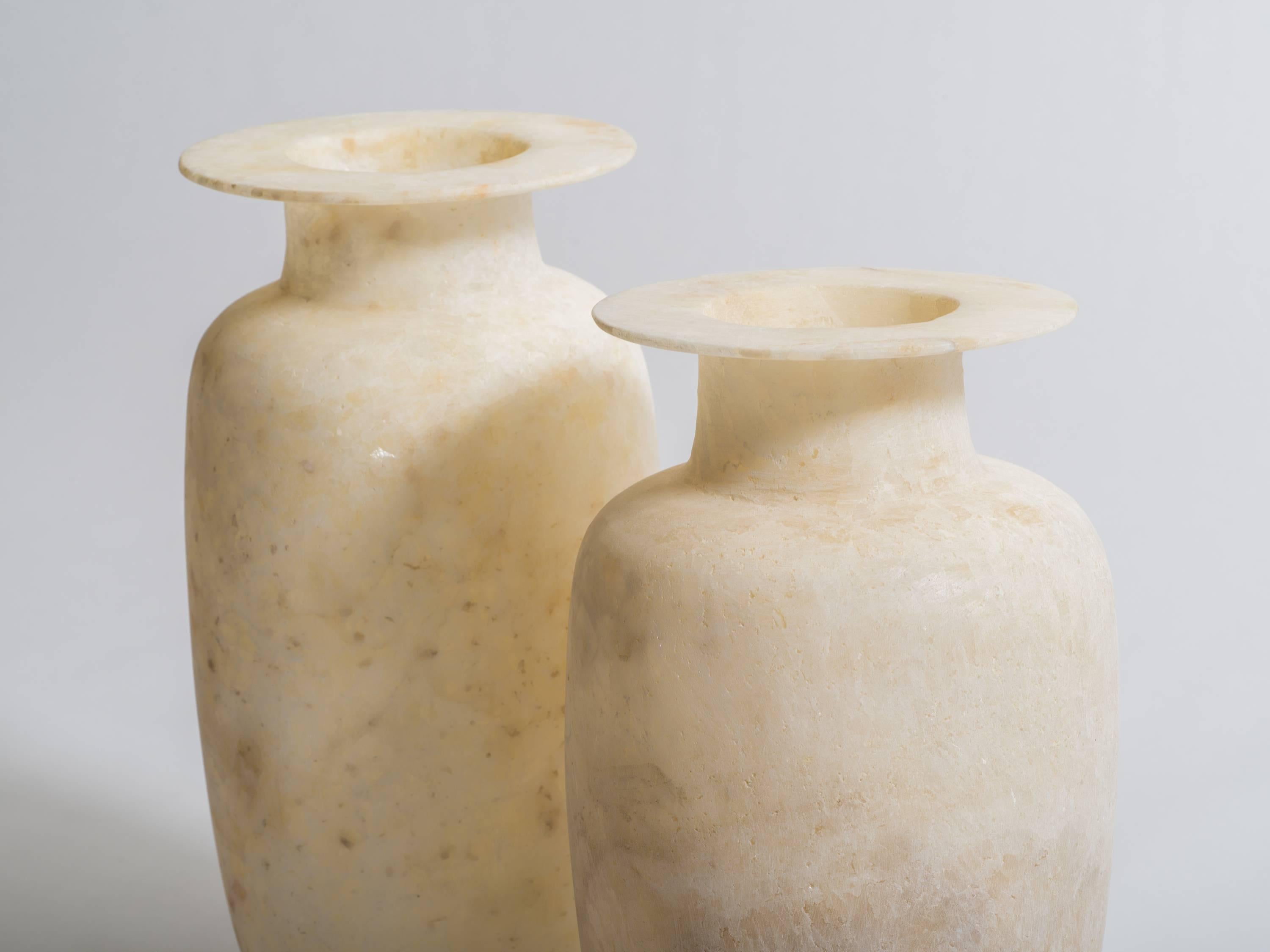 Pair of tall Egyptian alabaster ovoid urn vases with wide rimmed tops. Exquisitely hand-carved, the natural gypsum alabaster is milky white with natural veining. Tallest vase measures 17 inches height x 9.5 inches diameter. Second vase measures