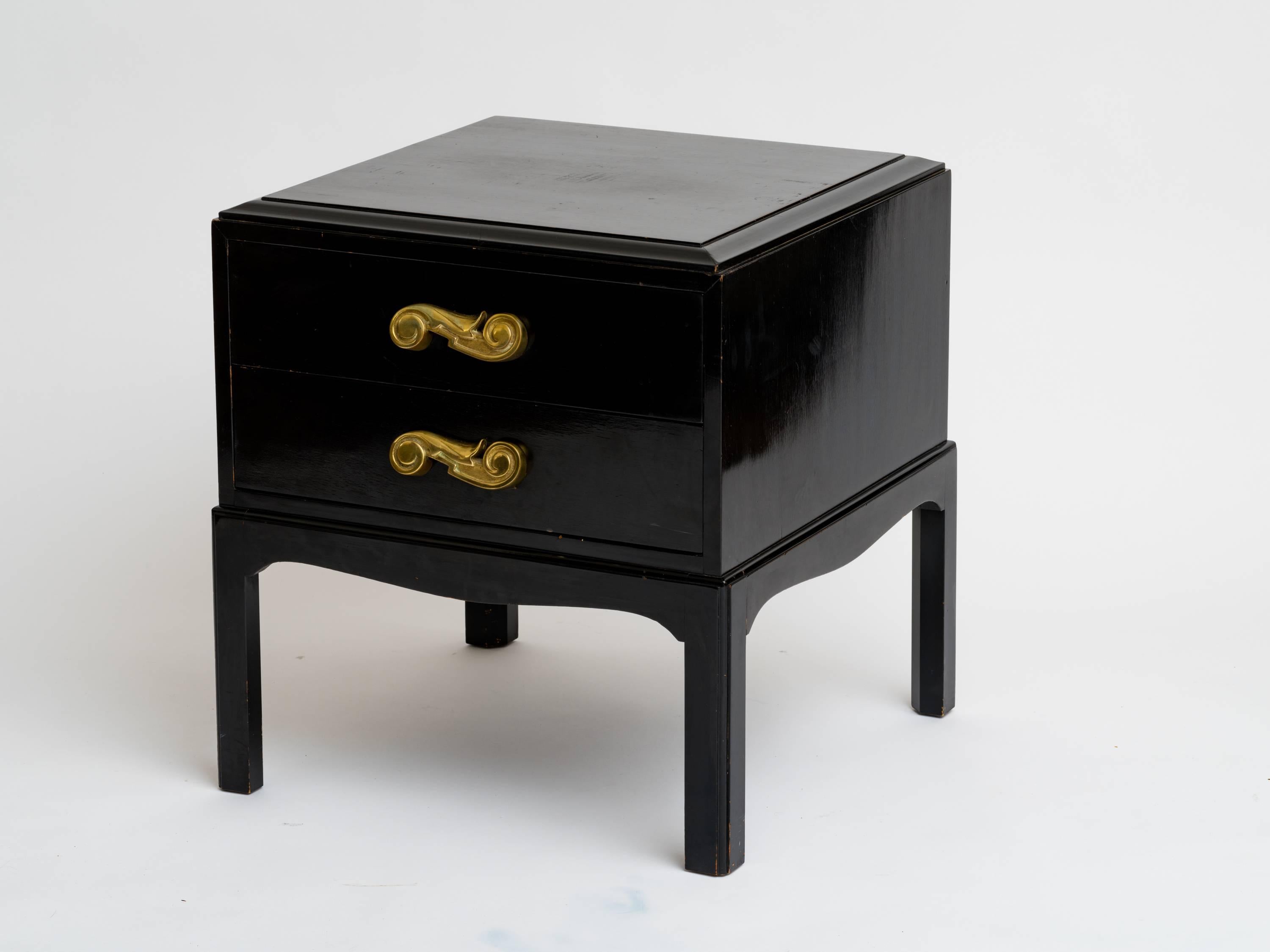 Stunning pair of Hollywood Regency ebonized end tables with bronze scroll drawer pulls. They stand on curved platform bases. Dated inside the wood frame, January 1949.