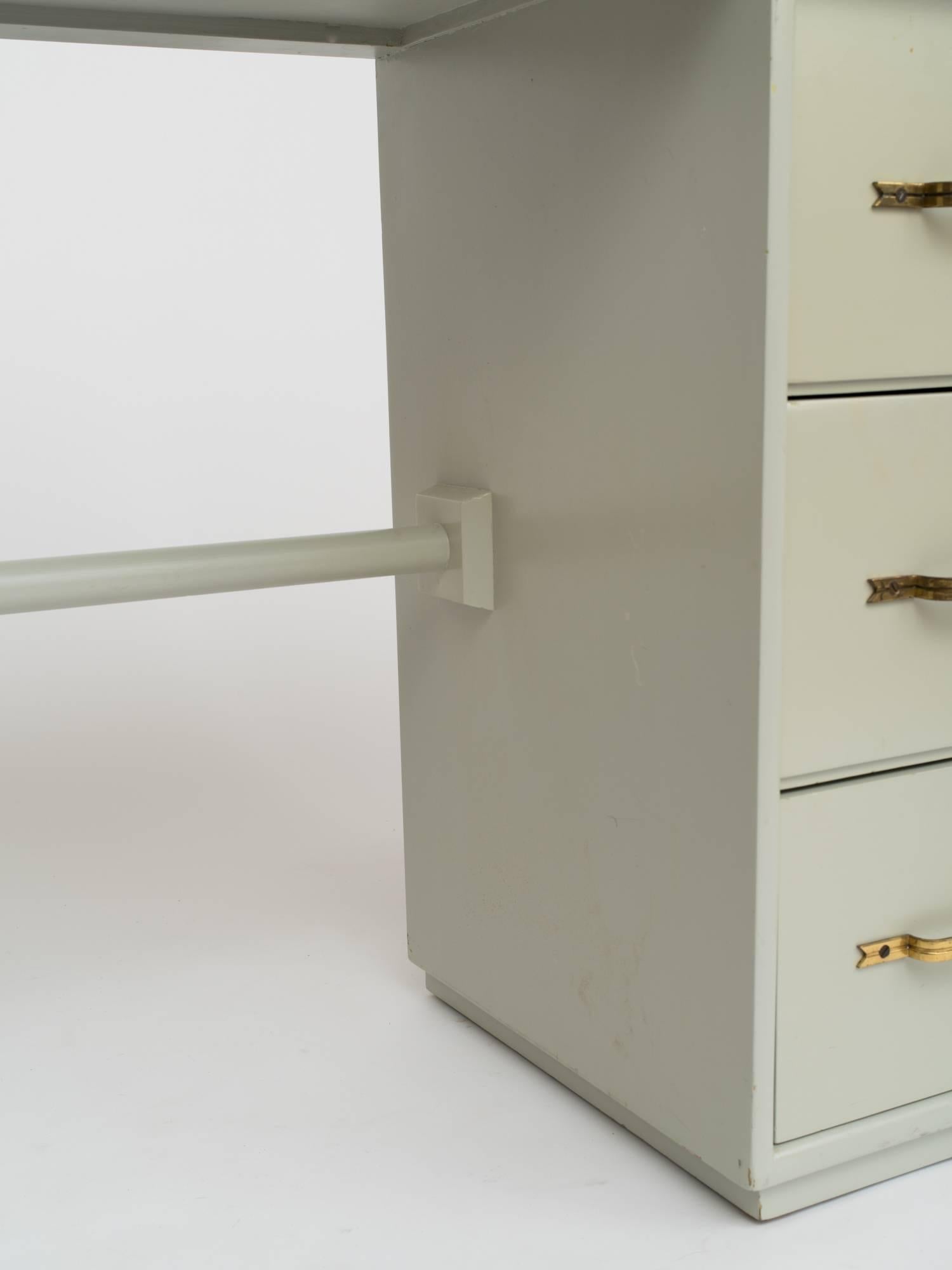 Tommi Parzinger zugeschriebener Winkelschreibtisch aus keladonlackiertem Holz, um 1950. Drei tiefe Schubladen mit charakteristischen Messinggriffen. Loch in der Oberseite, wo zuvor die eingebaute Lampe angebracht war. Lackschäden, Schreibtisch muss